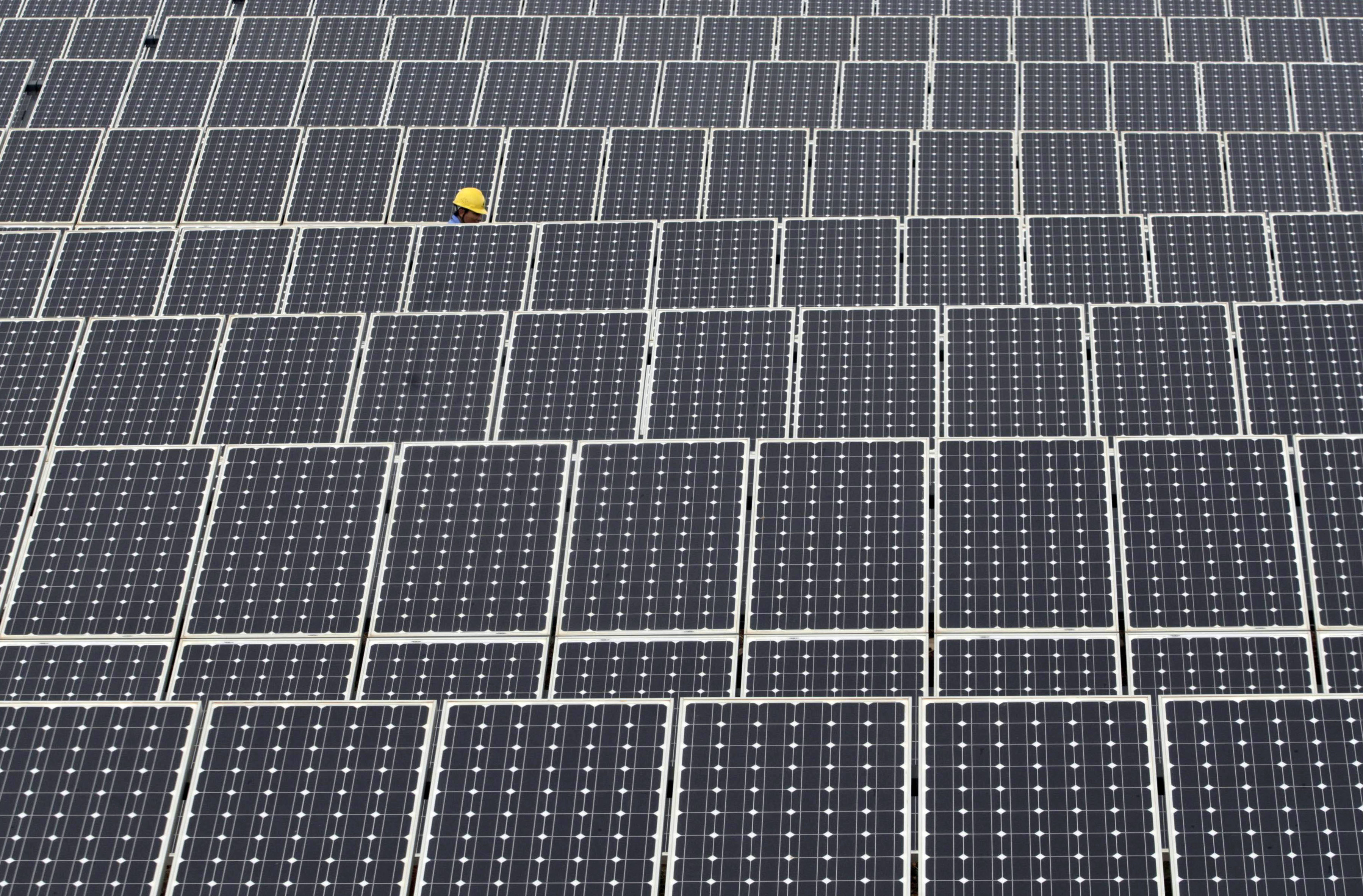 A labourer inspects solar panels at a solar power plant in Kunming