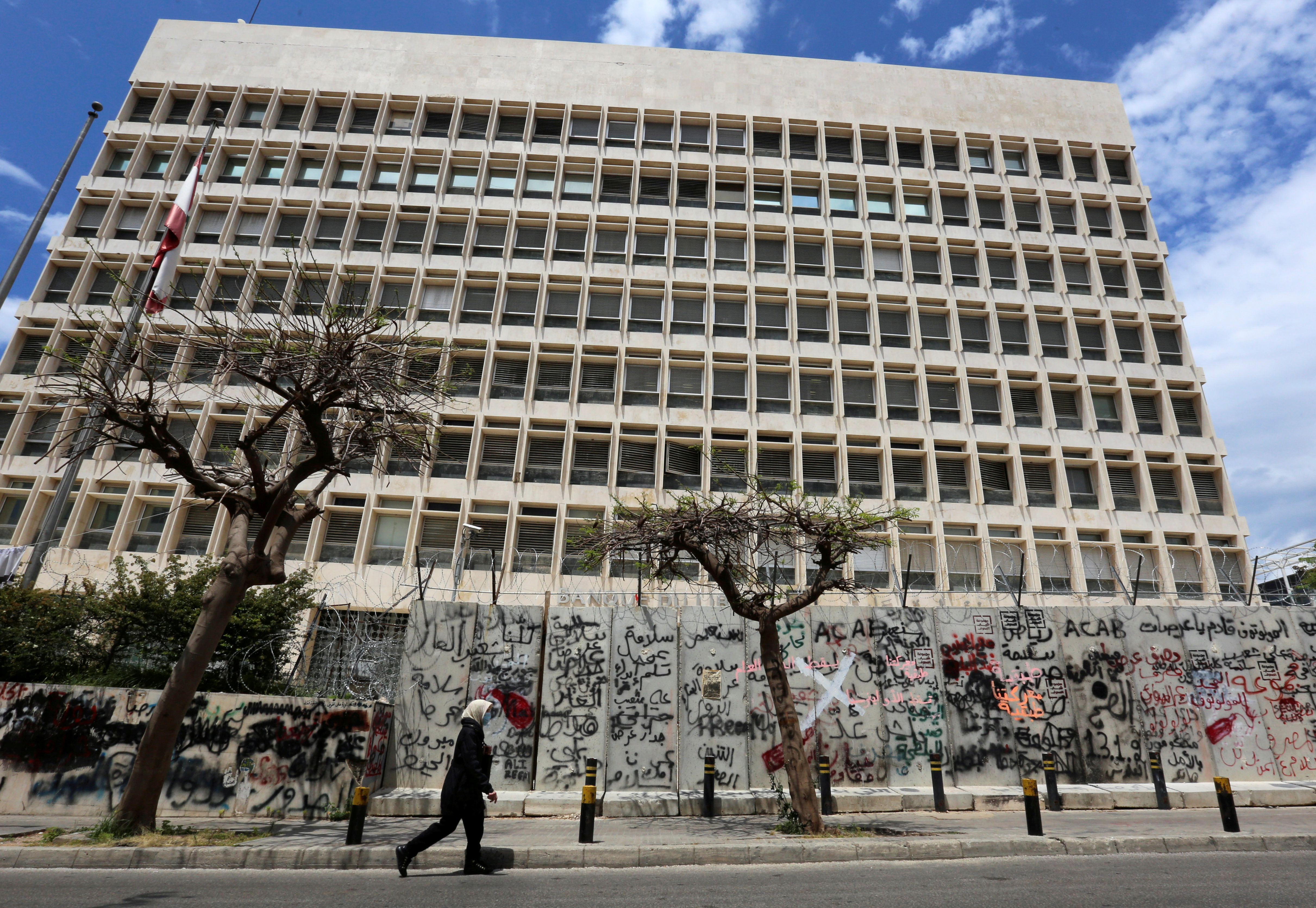 A woman wearing a protective mask walks past Central Bank building as Lebanon extends a shutdown to curb the spread of the coronavirus disease (COVID-19) in Beirut