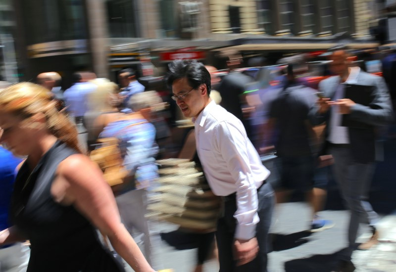 Pedestrians walk across a main road in a retail shopping area in central Sydney