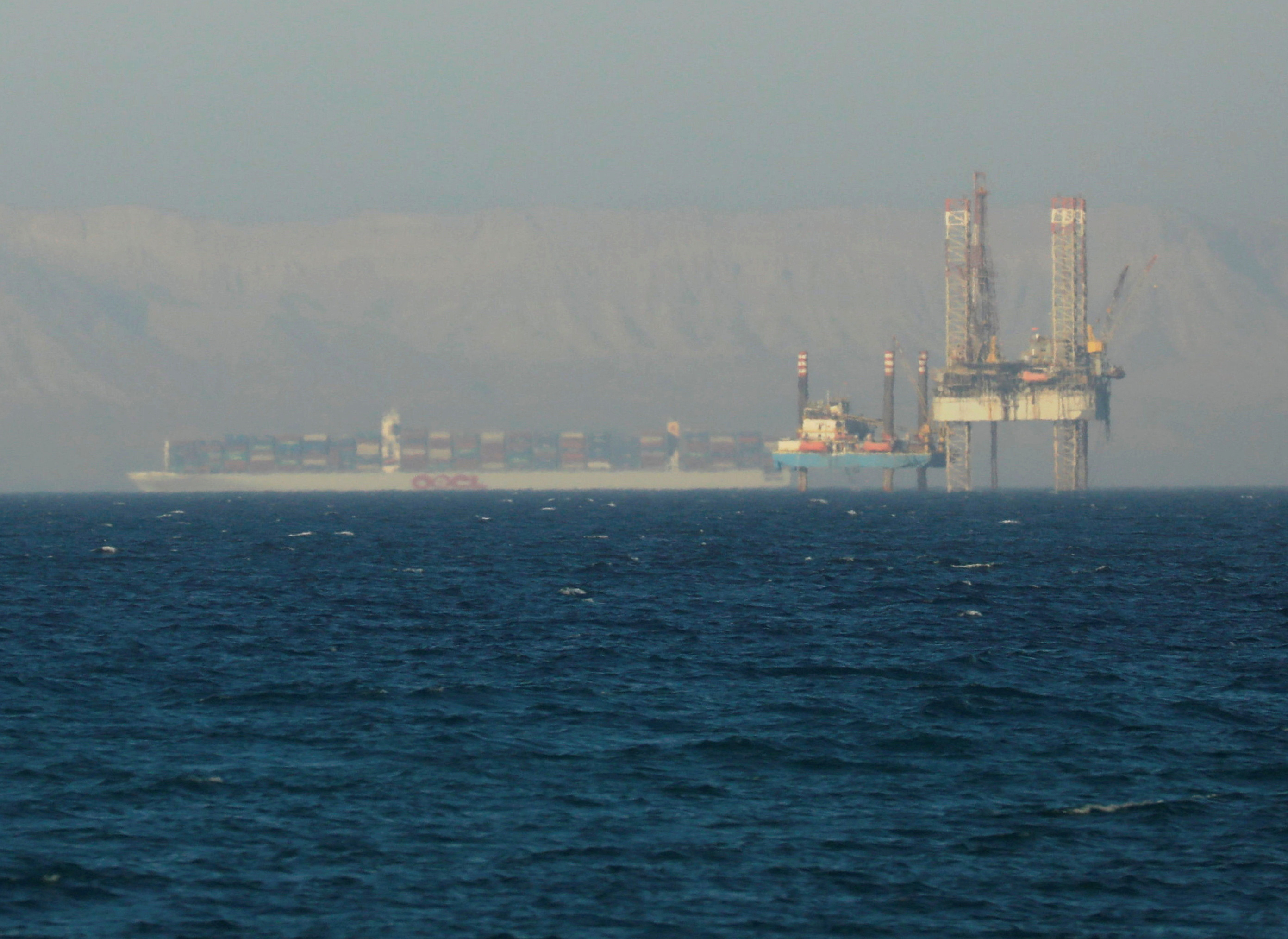 Container ship crosses an oil platform at the Gulf of Suez towards the Red Sea