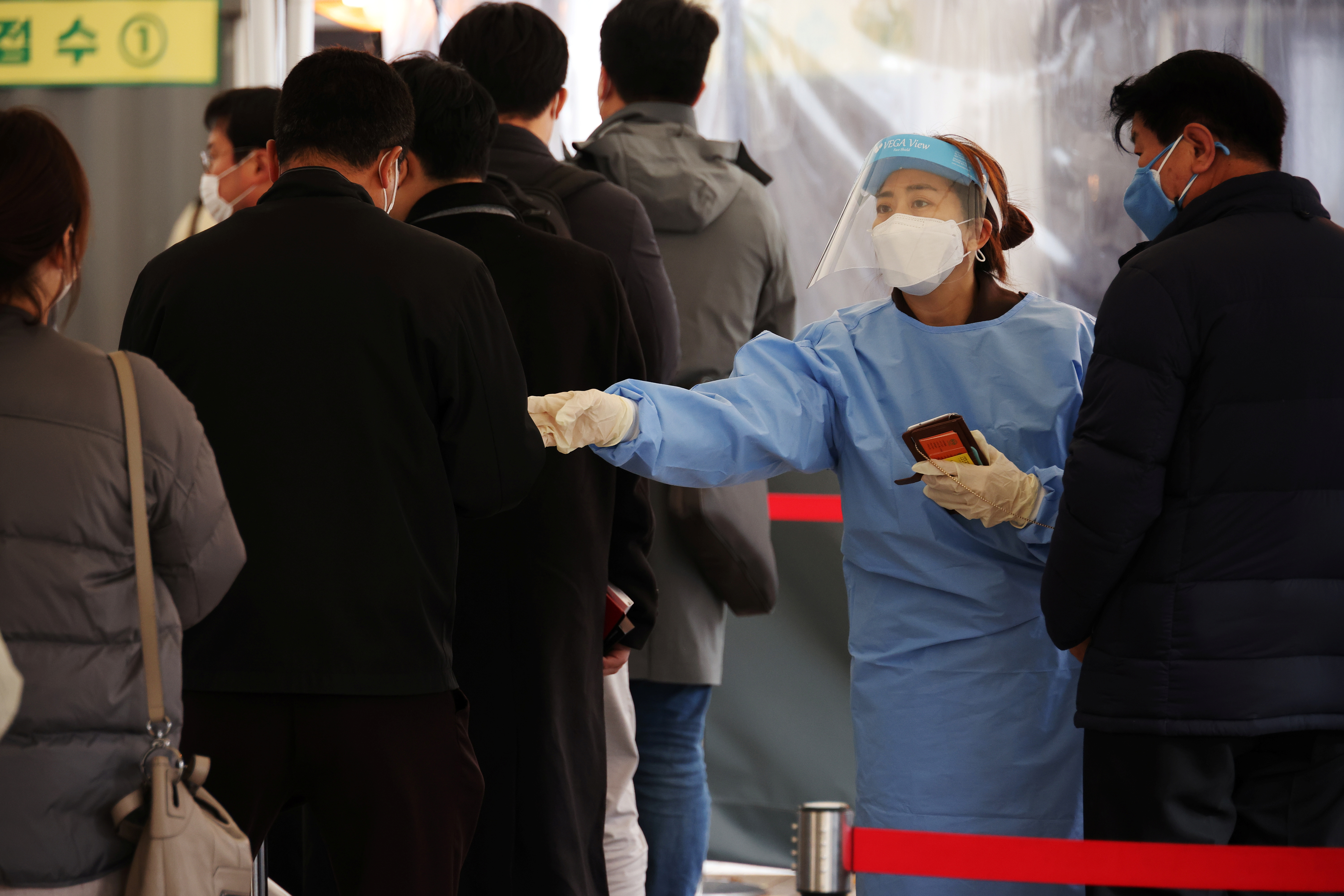A health worker directs people arriving to undergo coronavirus disease (COVID-19) tests, at a testing site in Seoul, South Korea, November 10, 2021. REUTERS/Kim Hong-Ji
