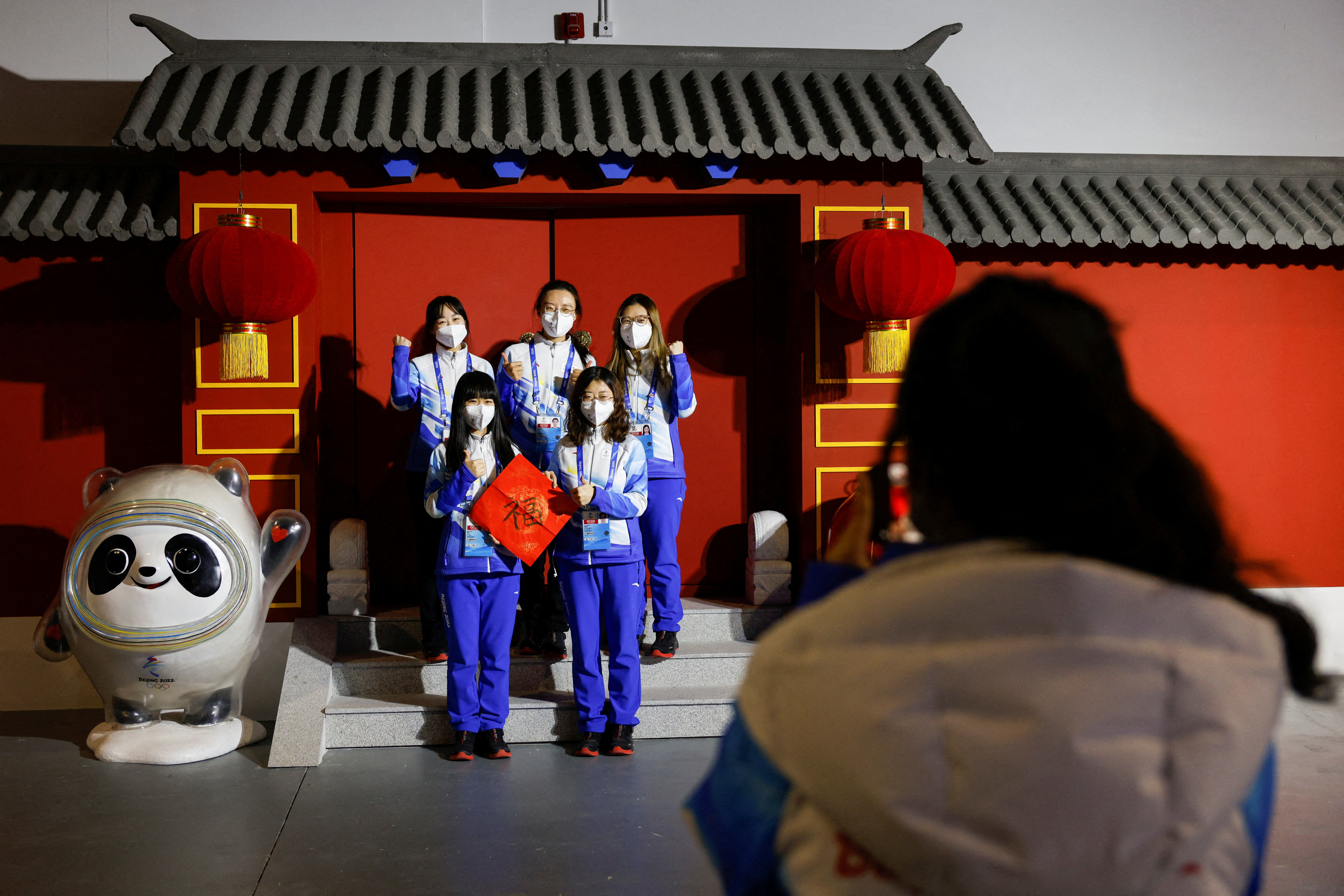 Volunteers pose for photo next to the installation of Bing Dwen Dwen and Shuey Rhon Rhon, mascots of the Beijing 2022 Winter Olympics and Paralympics, at the Main Press Centre, in Beijing