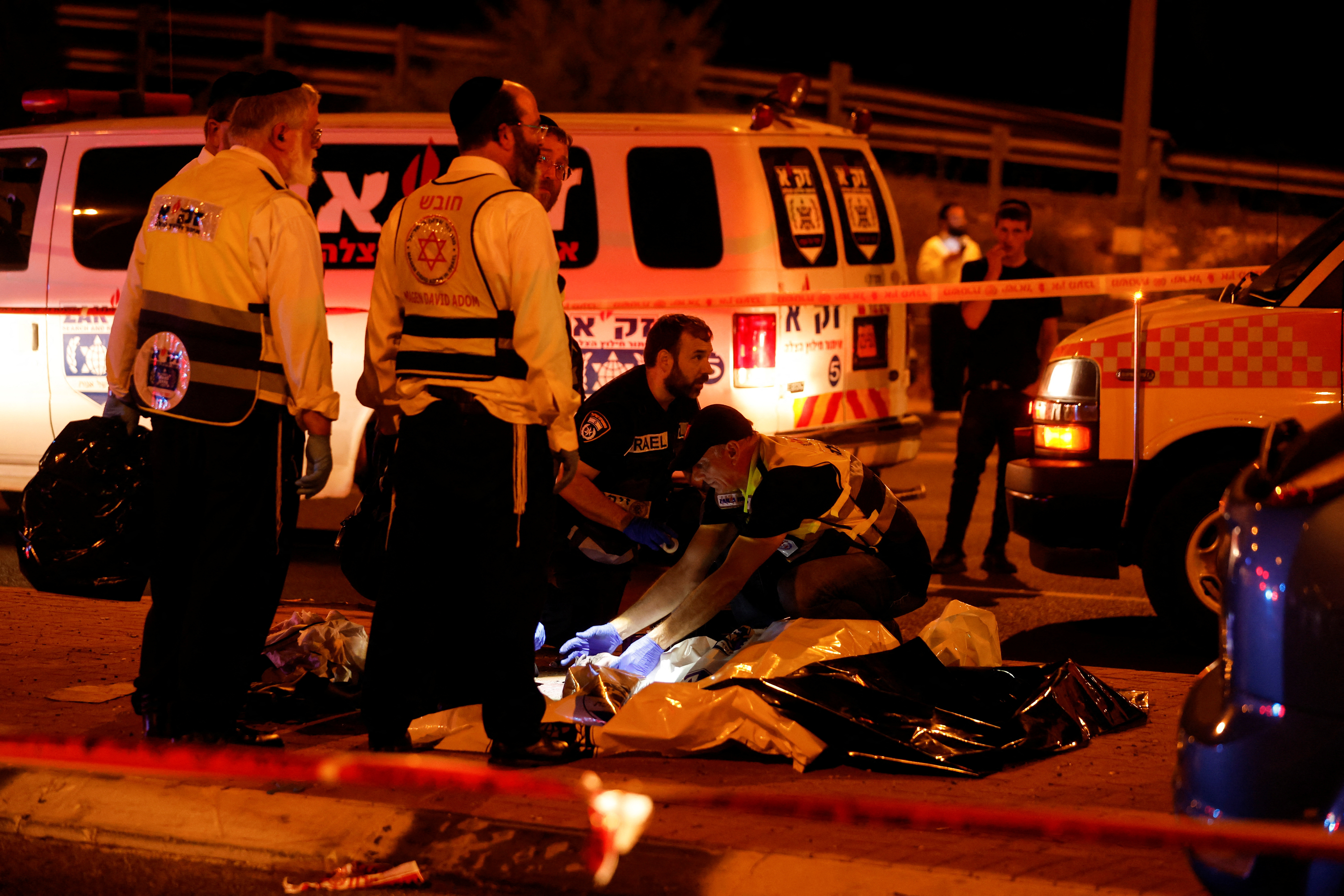 Israeli security personel check a dead body following an incident at the junction outside the city of Modi'in