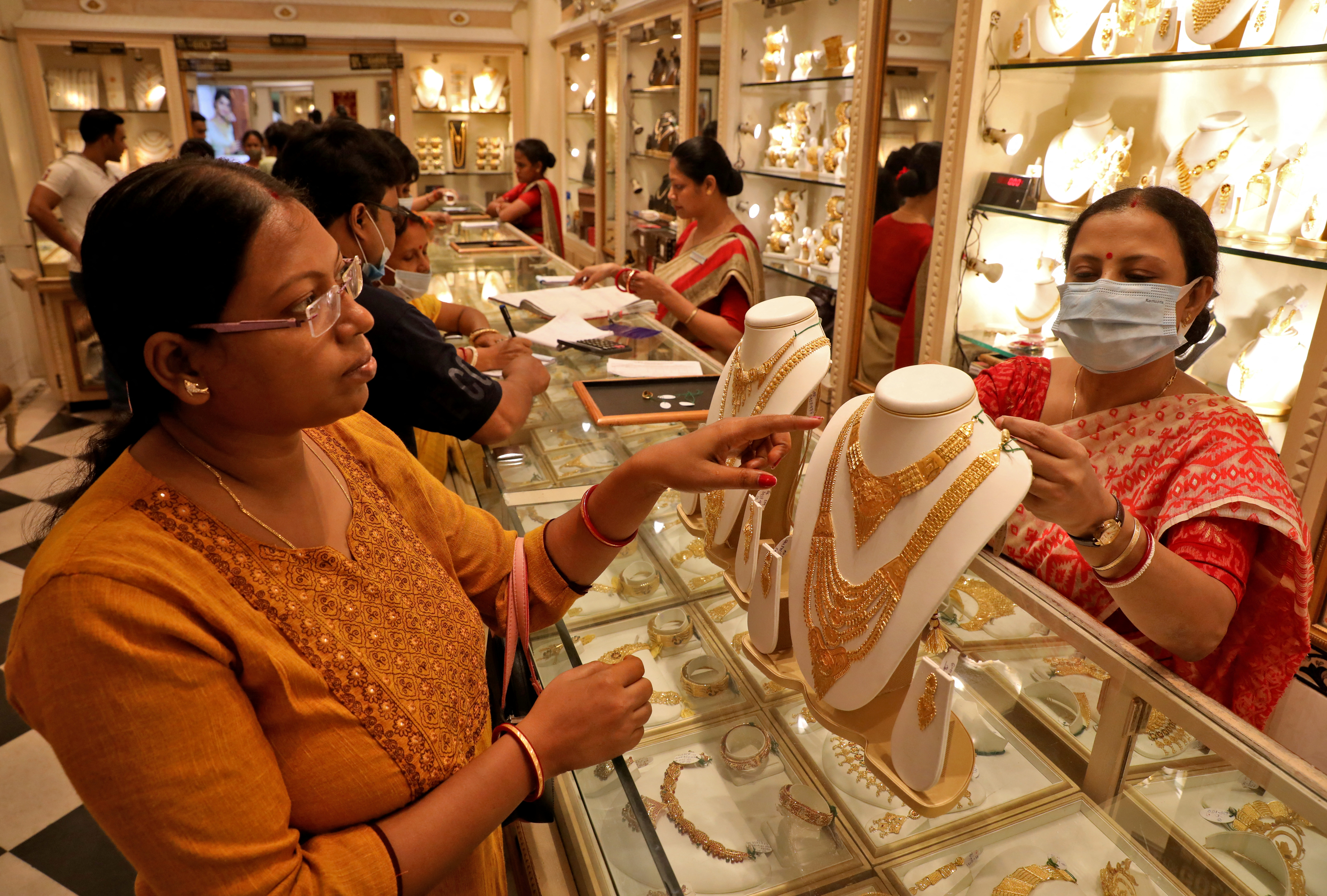 A customer checks a gold necklace before buying it at a jewellery showroom, in Kolkata