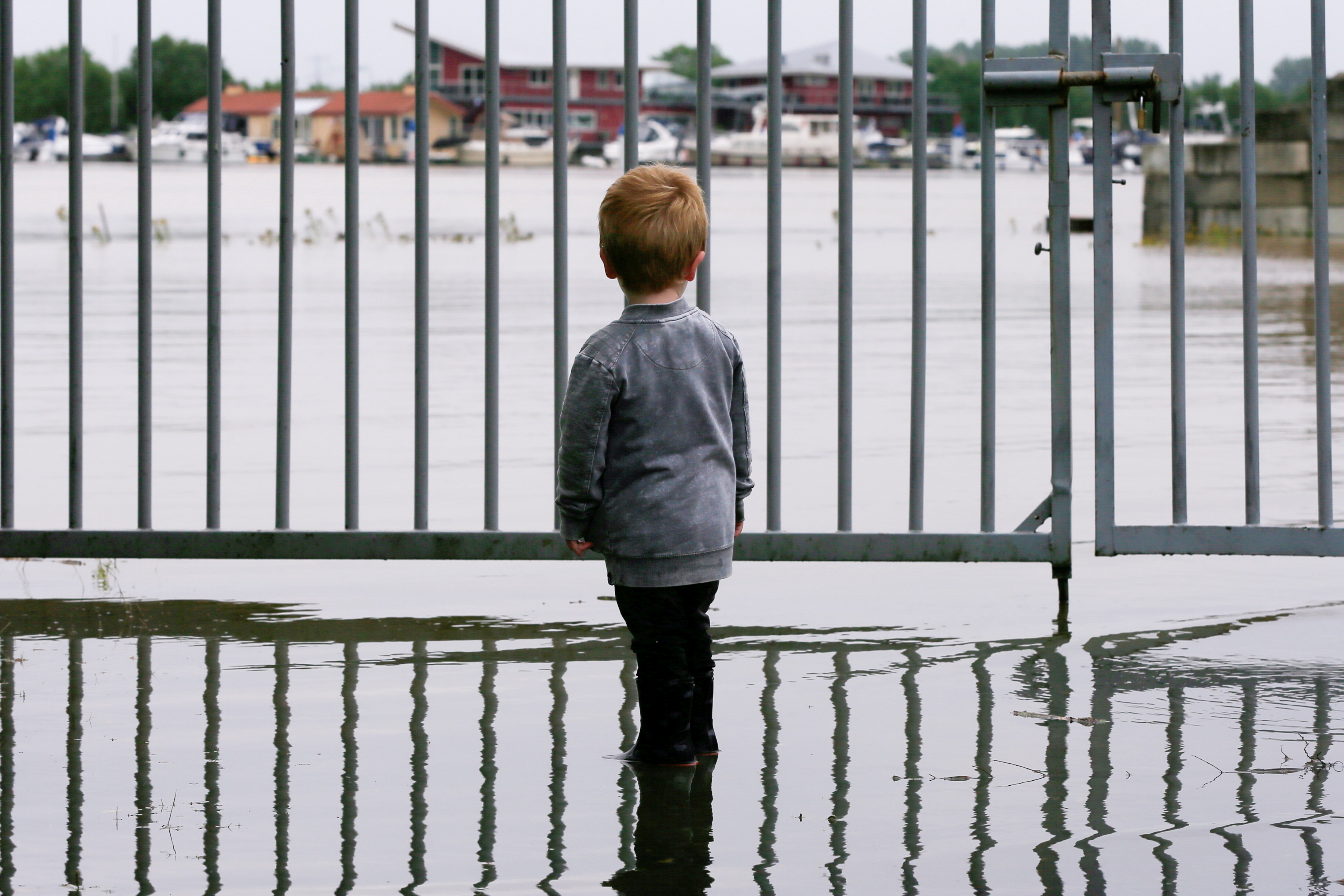 A child looks on as water floods through a fence in Wessem