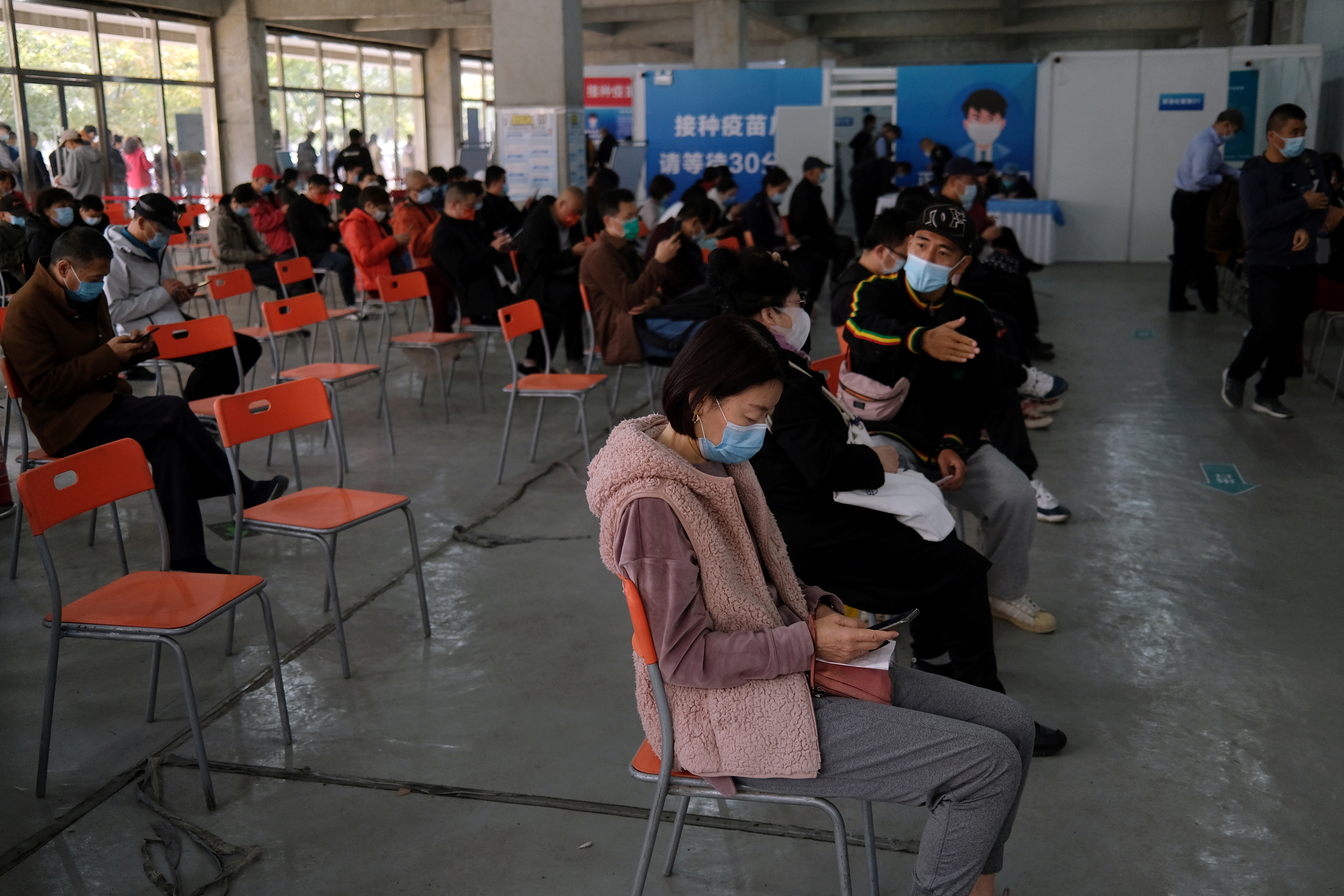 People wait at an observation area after receiving booster shots of COVID-19 vaccine at a vaccination site in Beijing