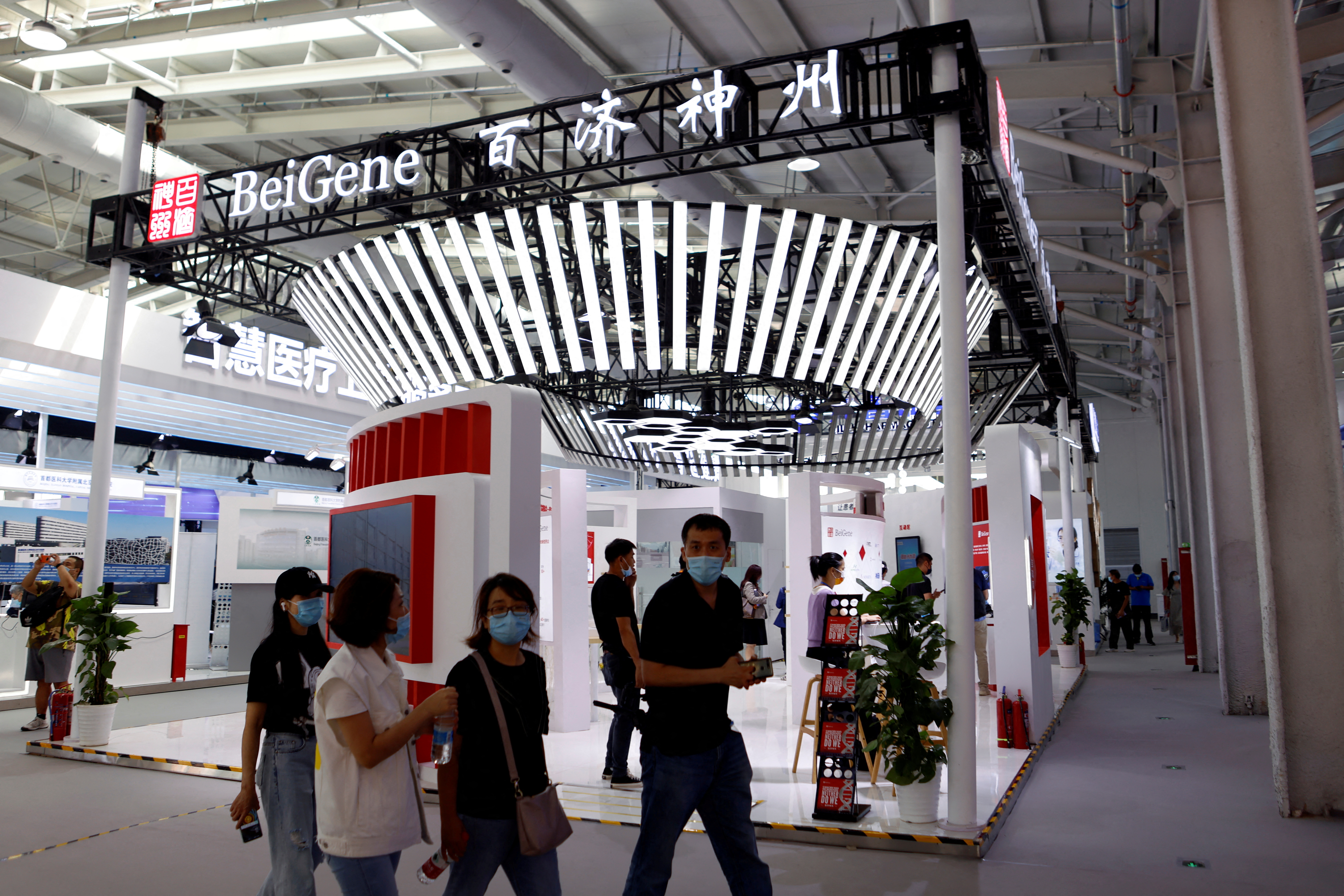People walk past a booth of biotech company Beigene in Beijing