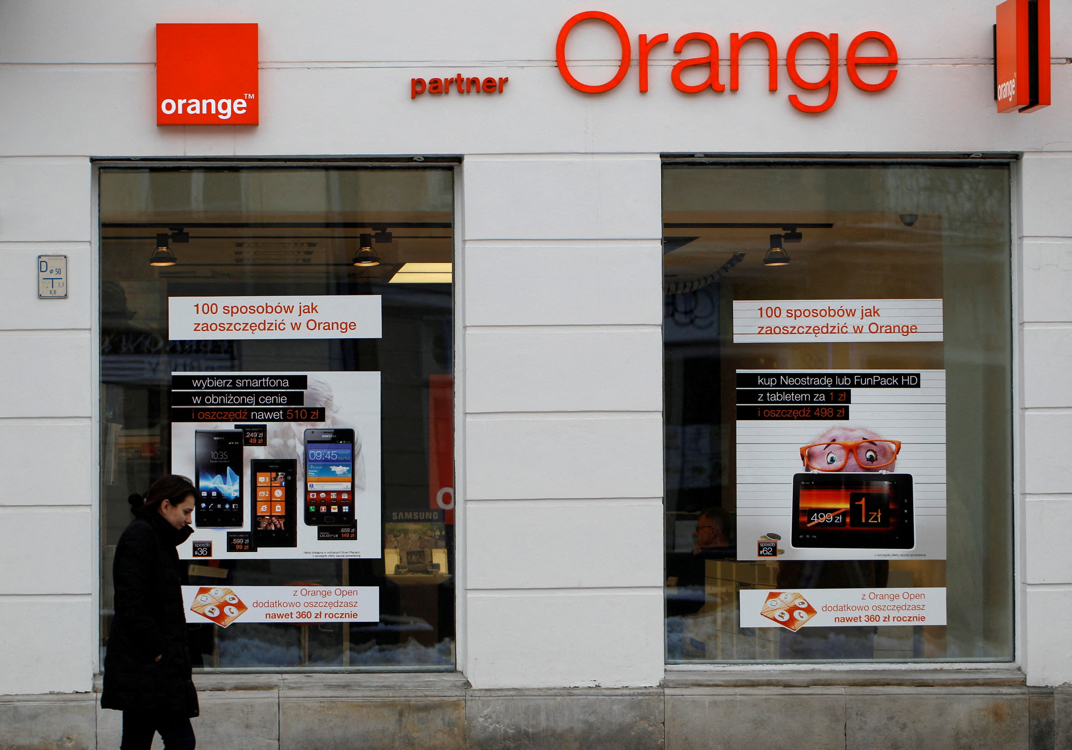 A woman passes in front of an Orange store in Warsaw