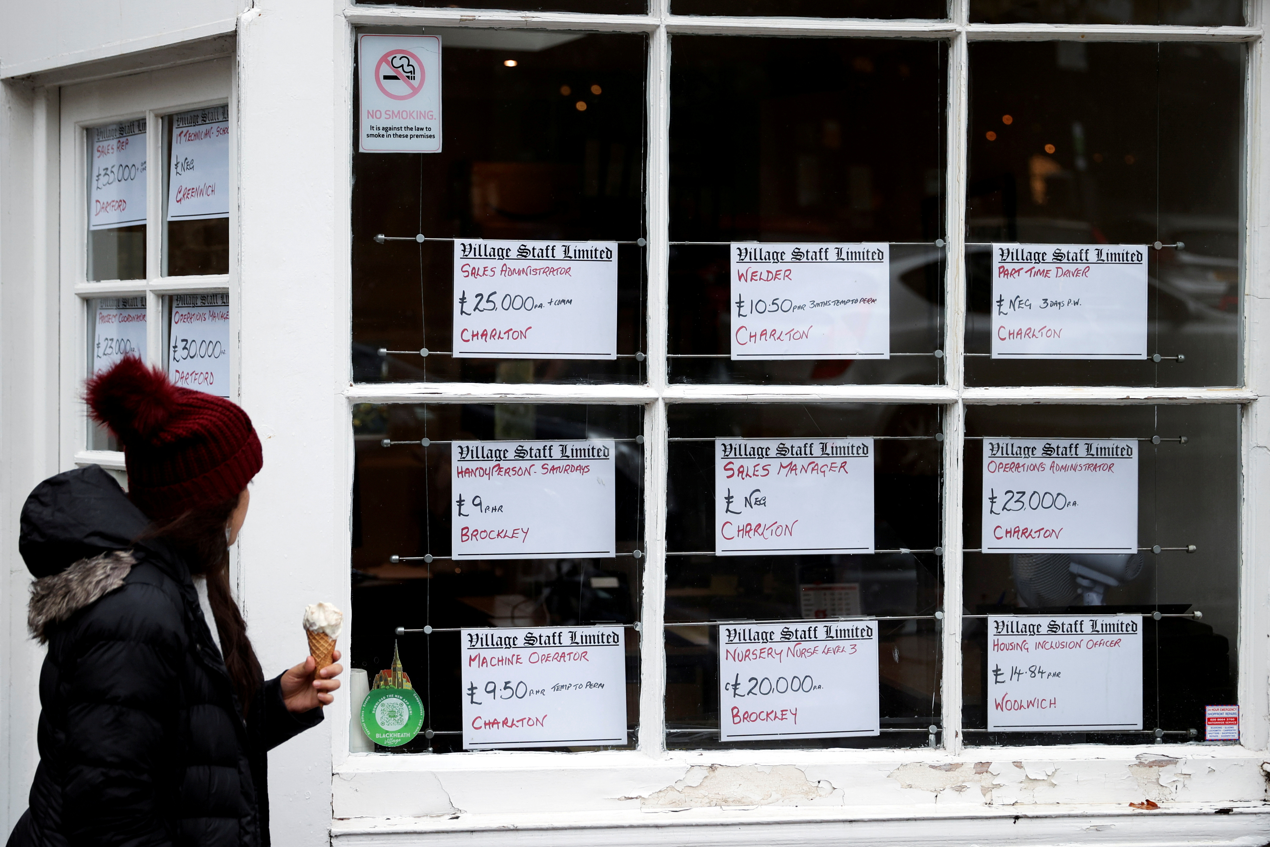 A person looks at advertisements in the window of a job agency in London