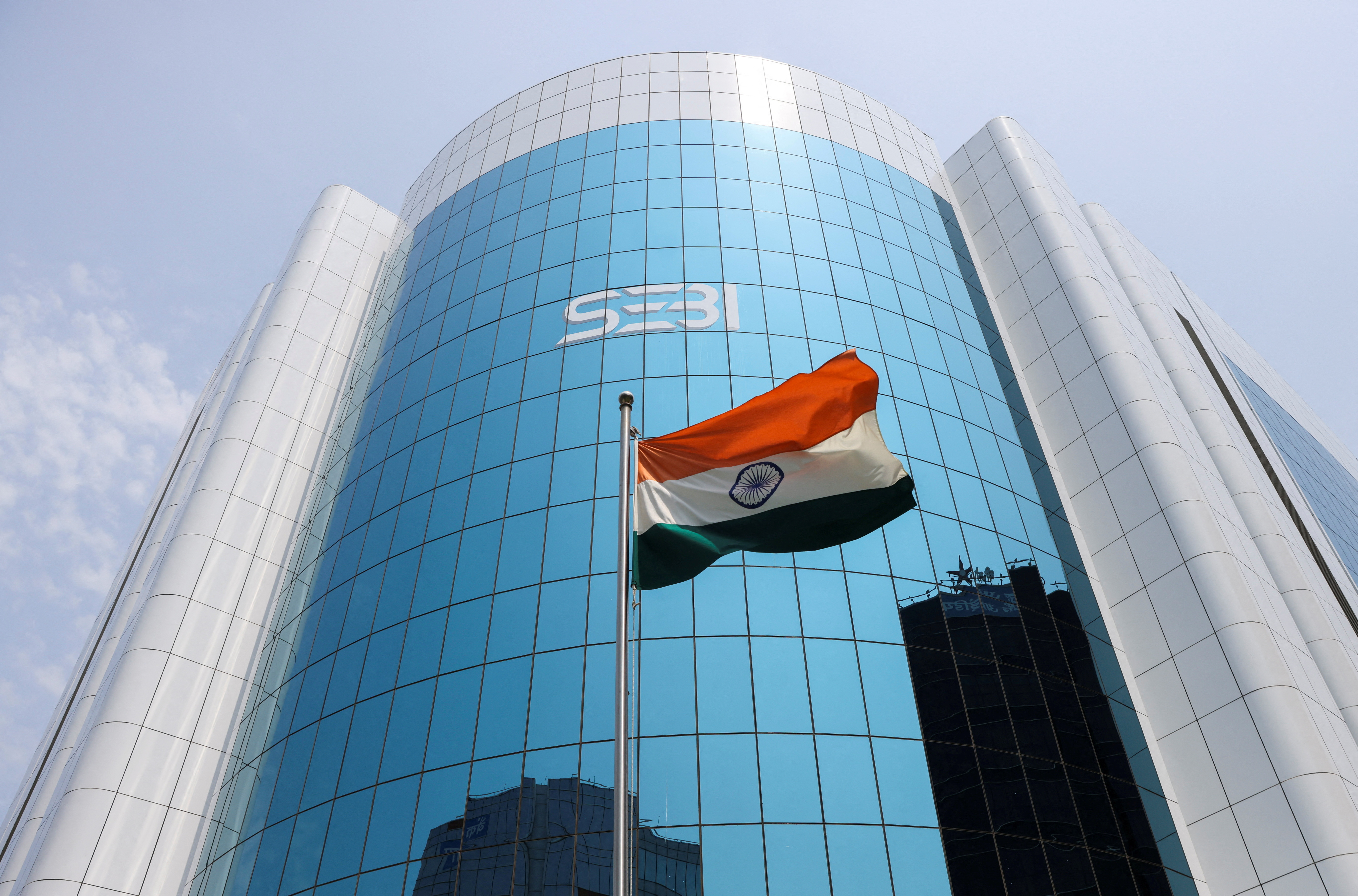 The Indian flag flies in front of the logo of the Securities and Exchange Board of India (SEBI) at its headquarters in Mumbai