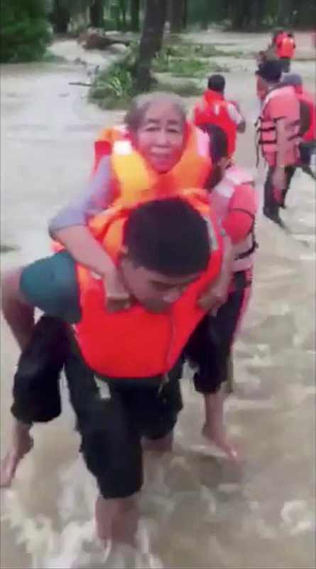 A woman is carried across floodwaters caused by tropical cyclone Kompasu during an evacuation assisted by the Philippine Coast Guard (PCG) at Brooke's Point, Palawan