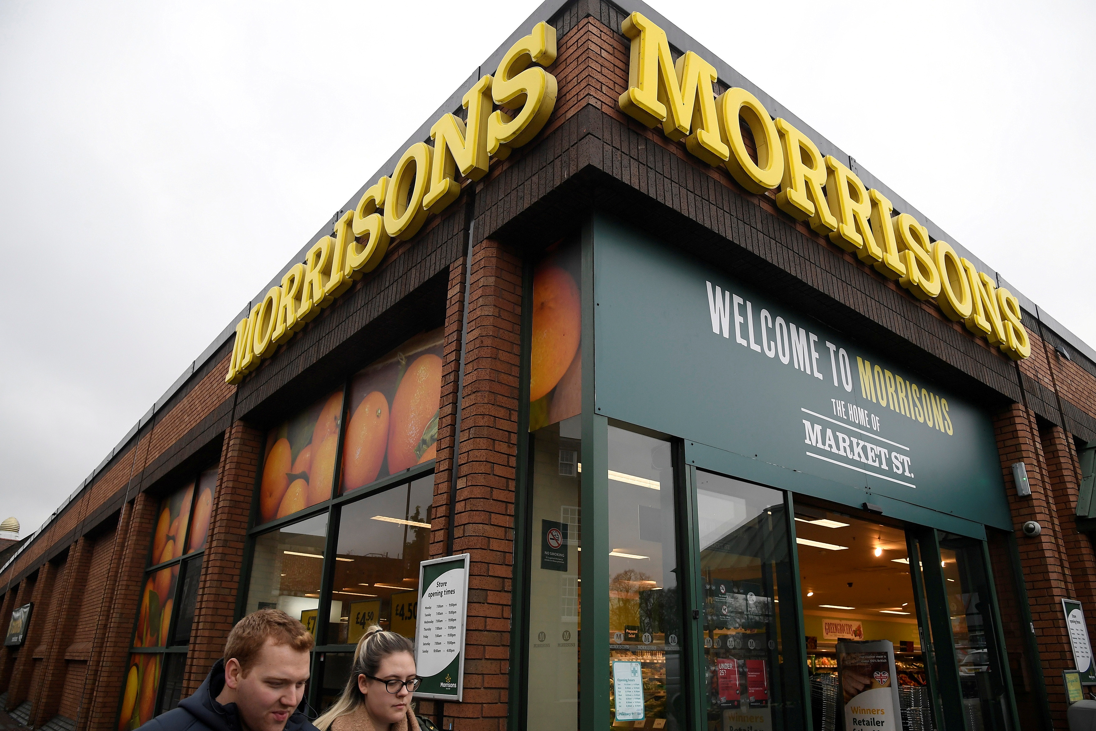 Shoppers walk past a branch of the food retailer Morrisons in west London, Britain