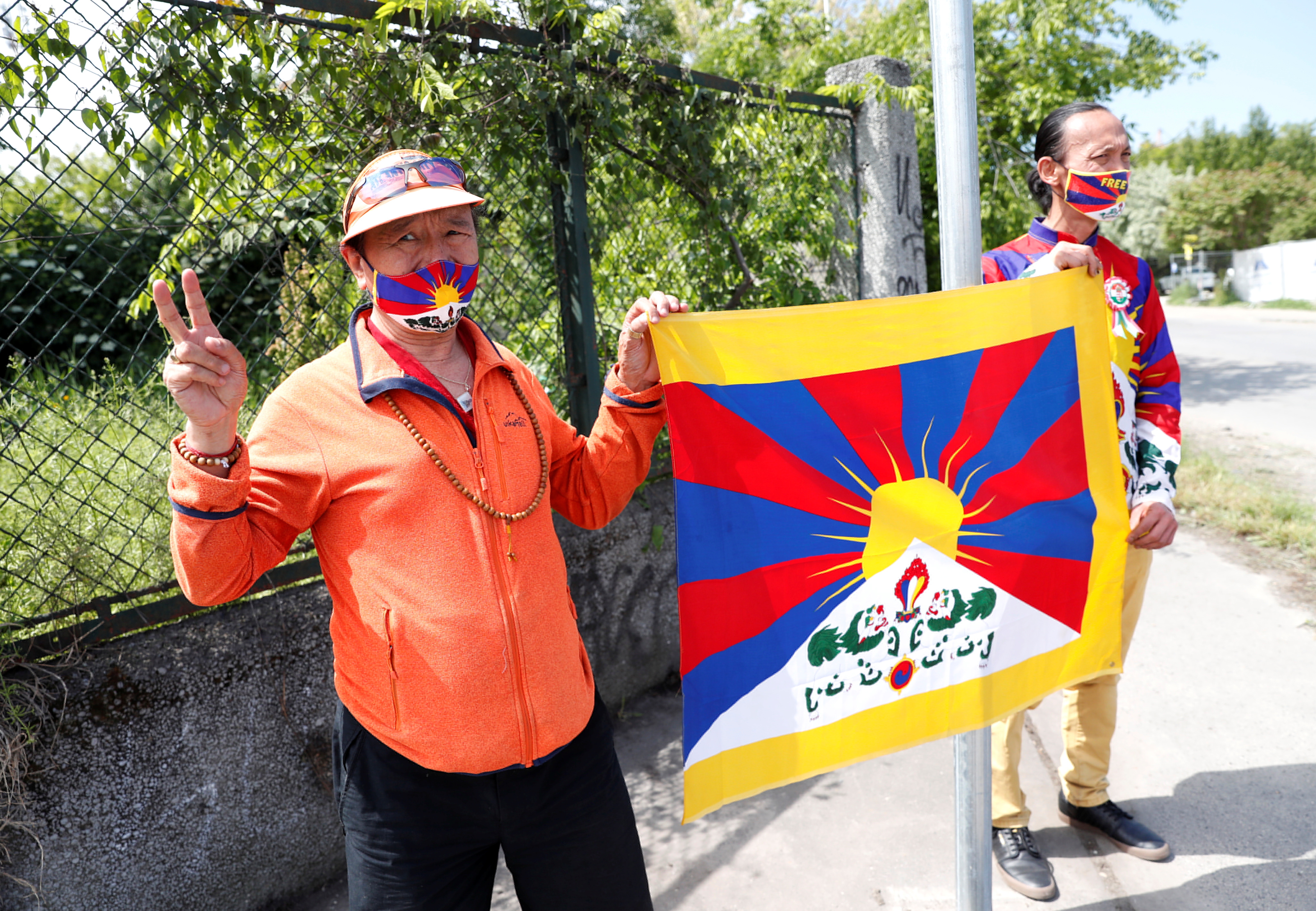 Activists hold a Tibetan flag next to a street sign in a street renamed 'Martyrs of Uyghur' in Budapest