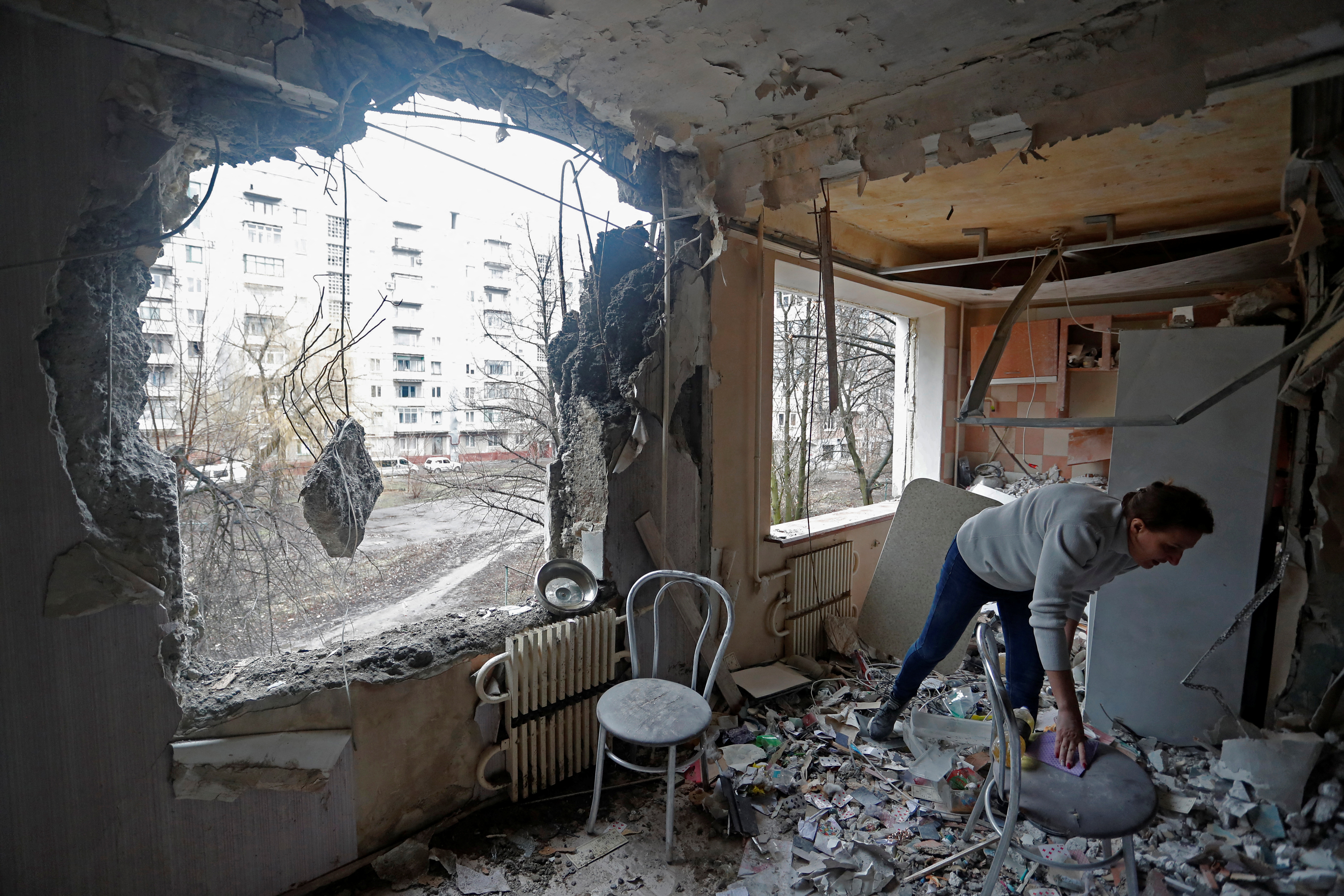 A woman inspects debris inside an apartment of a residential building, which locals said was damaged by recent shelling, in Horlivka