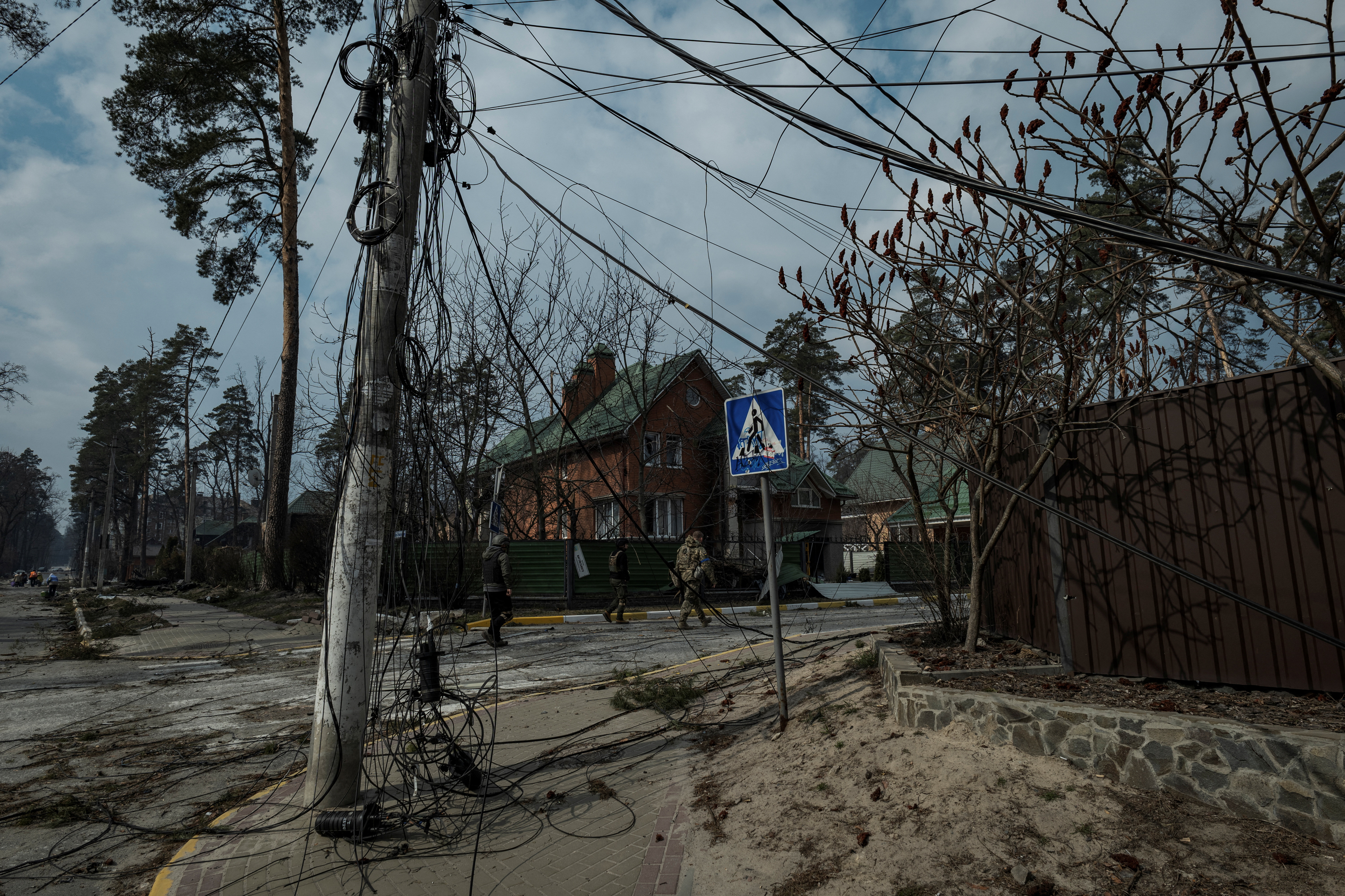 Men walk across a residential area damaged by heavy shelling in Irpin