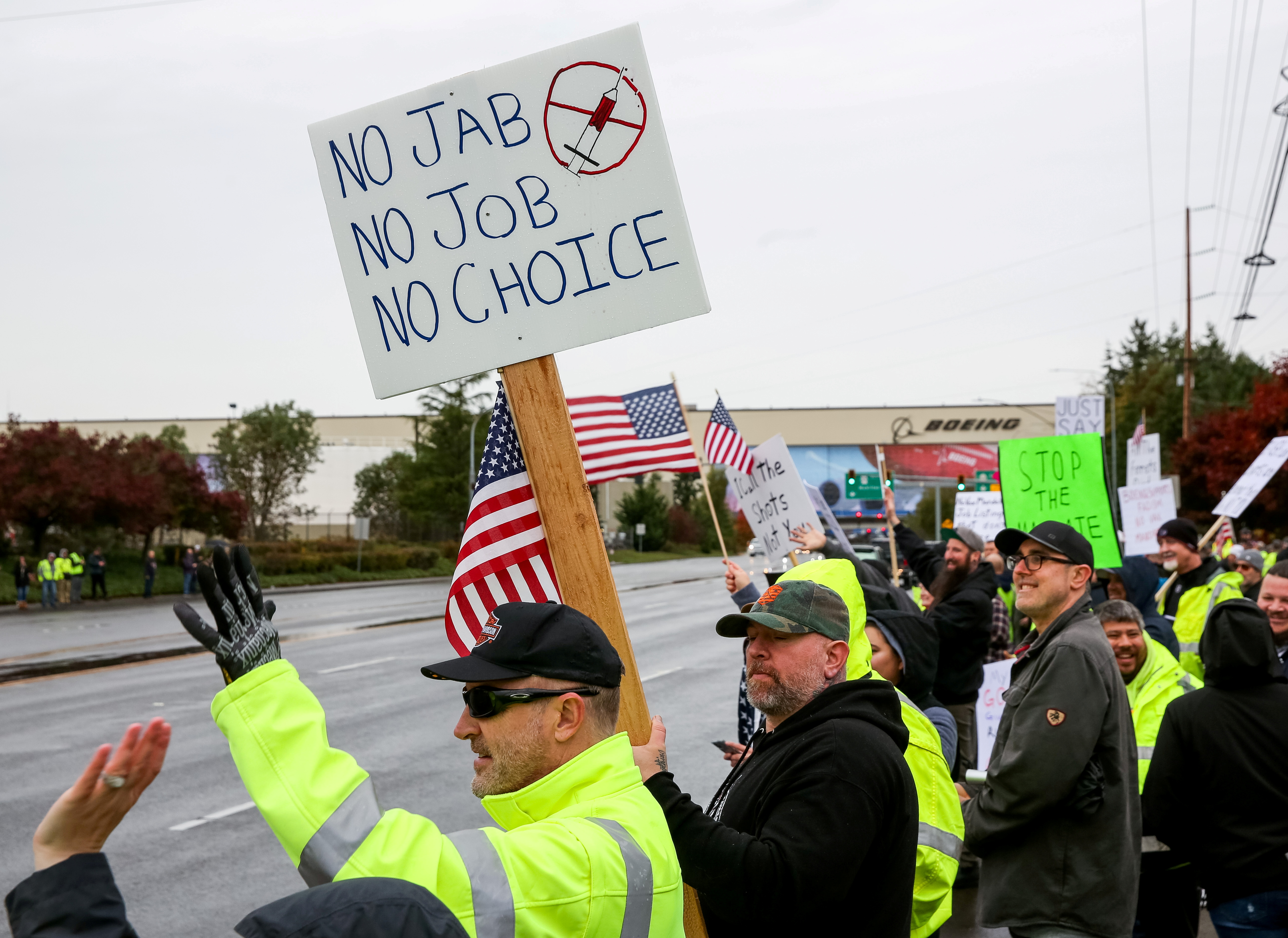 Boeing employees and others line the street with signs and American flags as they protest the company's coronavirus disease (COVID-19) vaccine mandate, outside the Boeing facility in Everett, Washington, October 15, 2021.  REUTERS/Lindsey Wasson