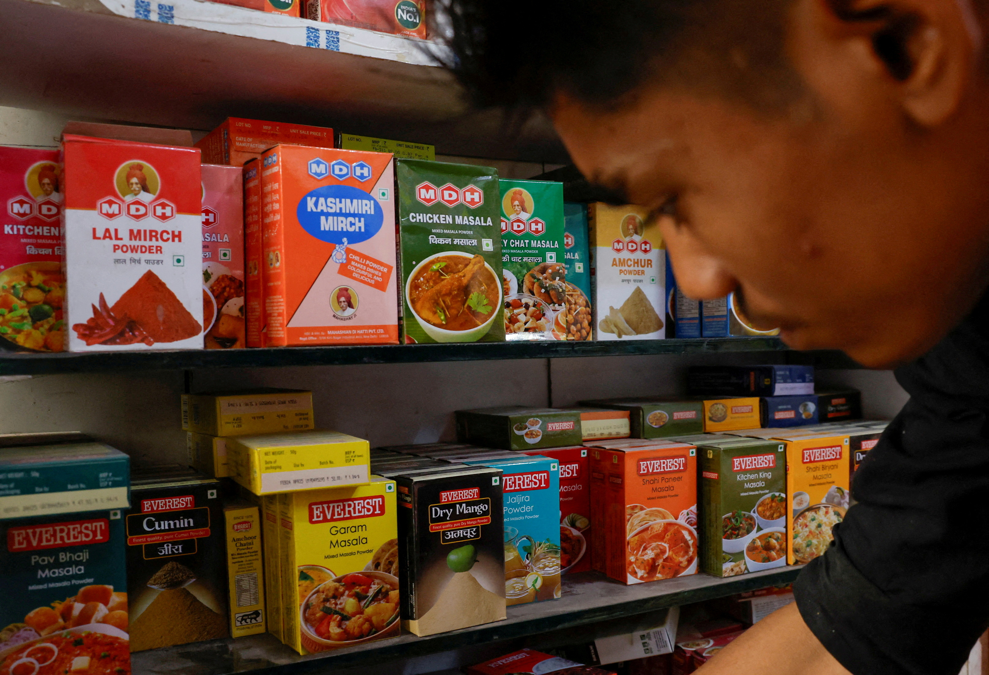 FILE PHOTO: A man stands near the spice boxes of MDH and Everest kept on the shelf of a shop at a market in New Delhi