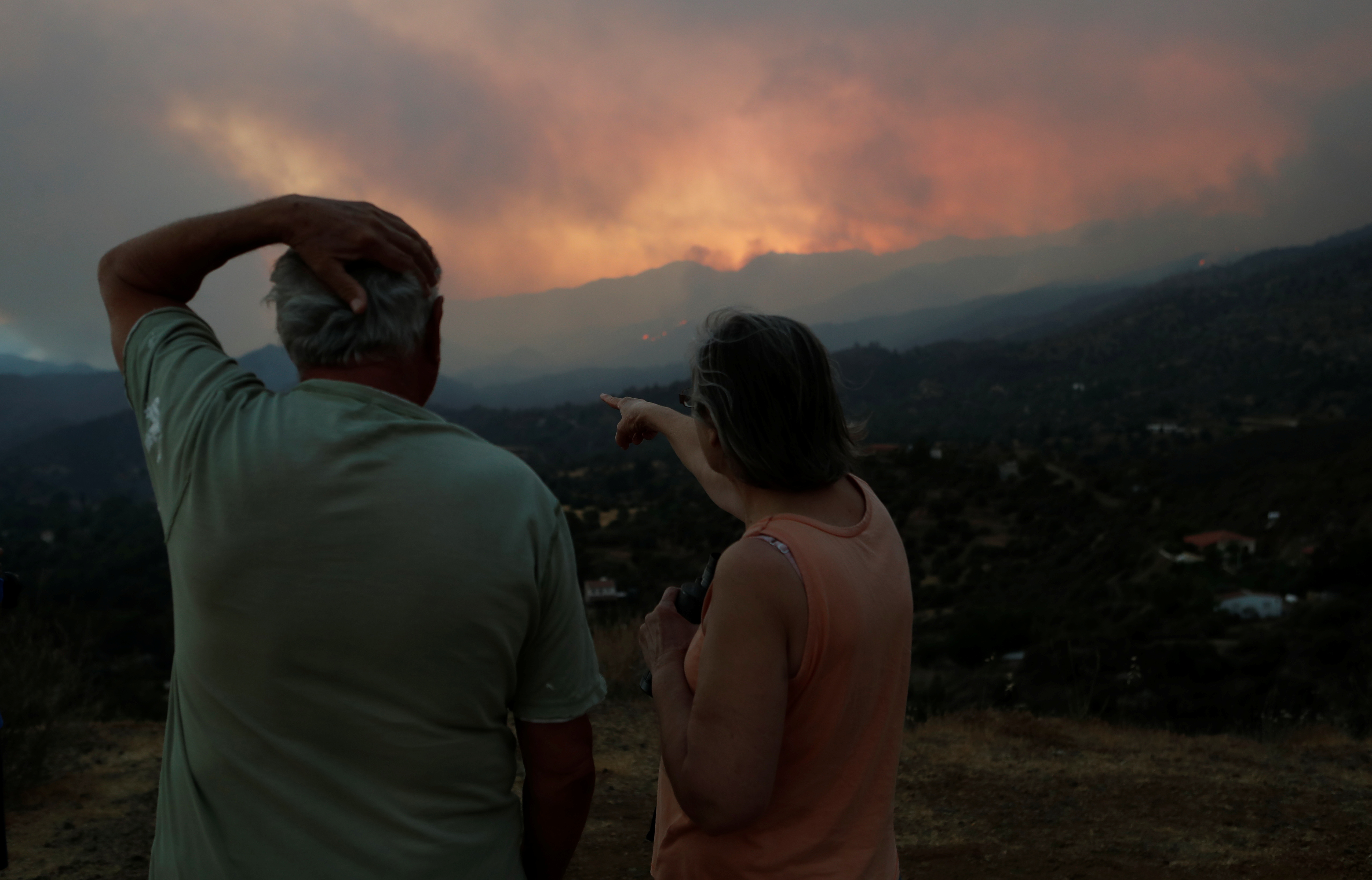 People watch a wildfire in the Larnaca mountain region