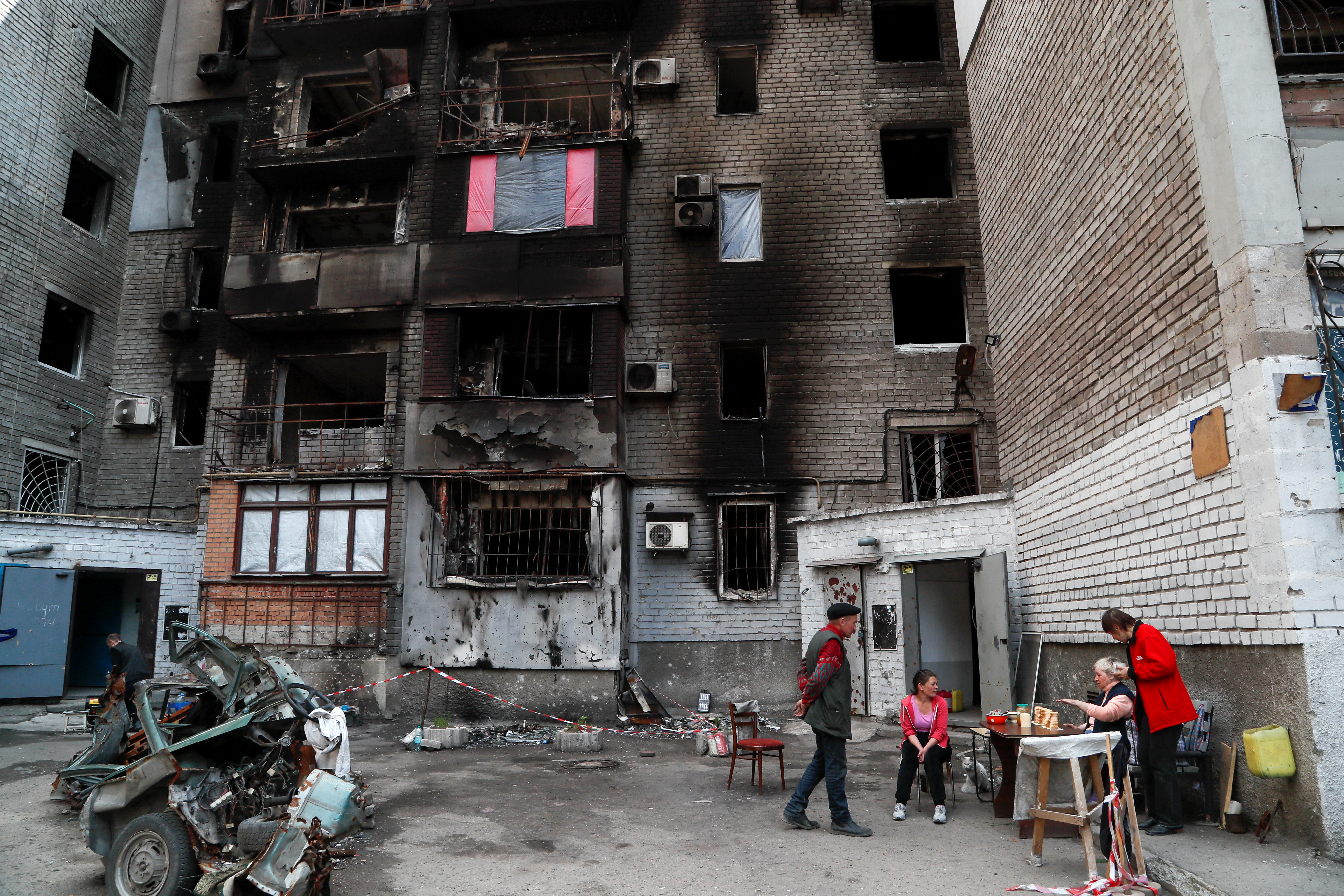 Local residents gather outside a damaged apartment building in Mariupol
