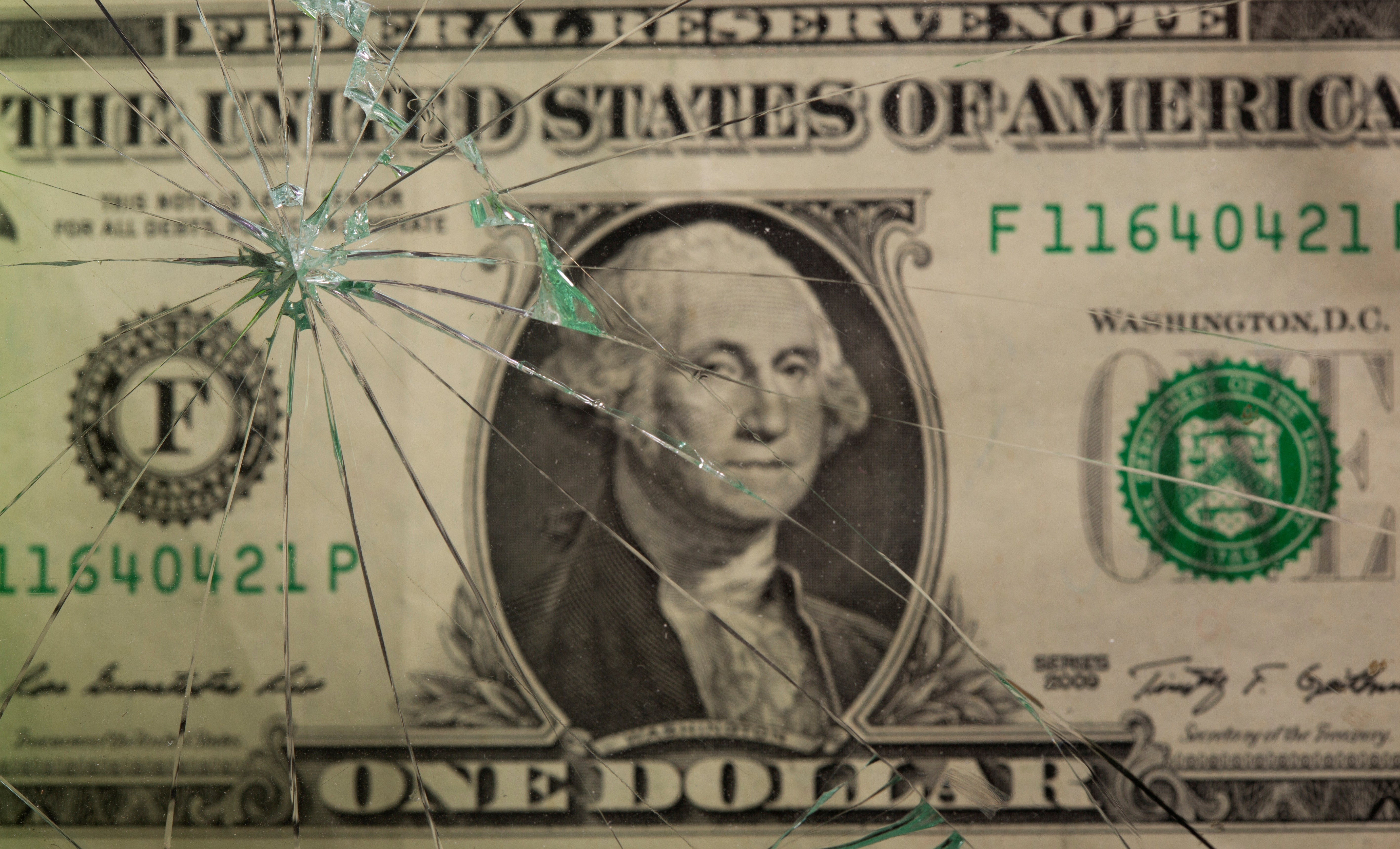 One U.S. dollar banknote is pictured through broken glass in this illustration taken June 25, 2021. REUTERS/Dado Ruvic/Illustration/File Photo