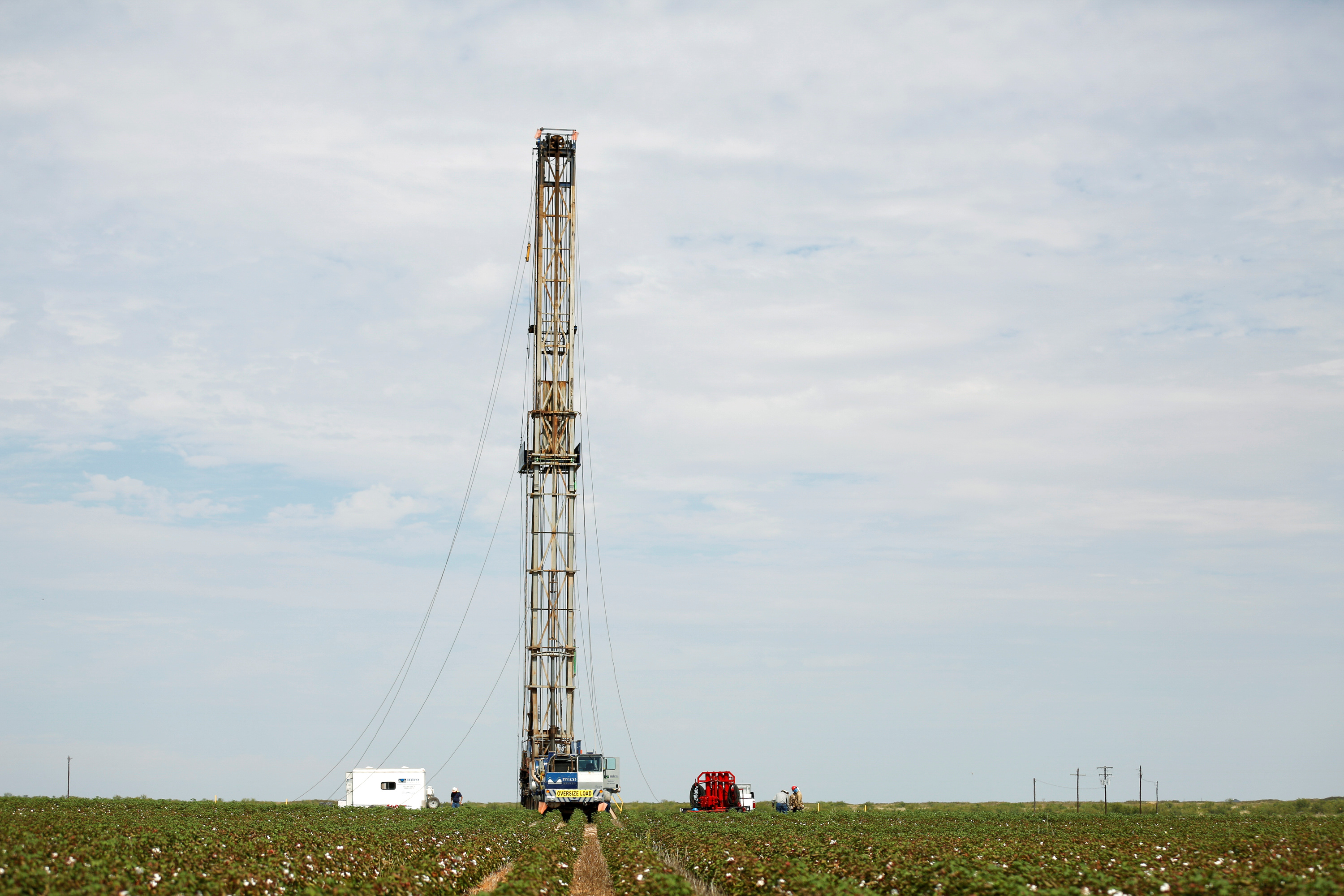 A pulling rig is erected at an oil well in the middle of a cotton field to swab the well in Seminole