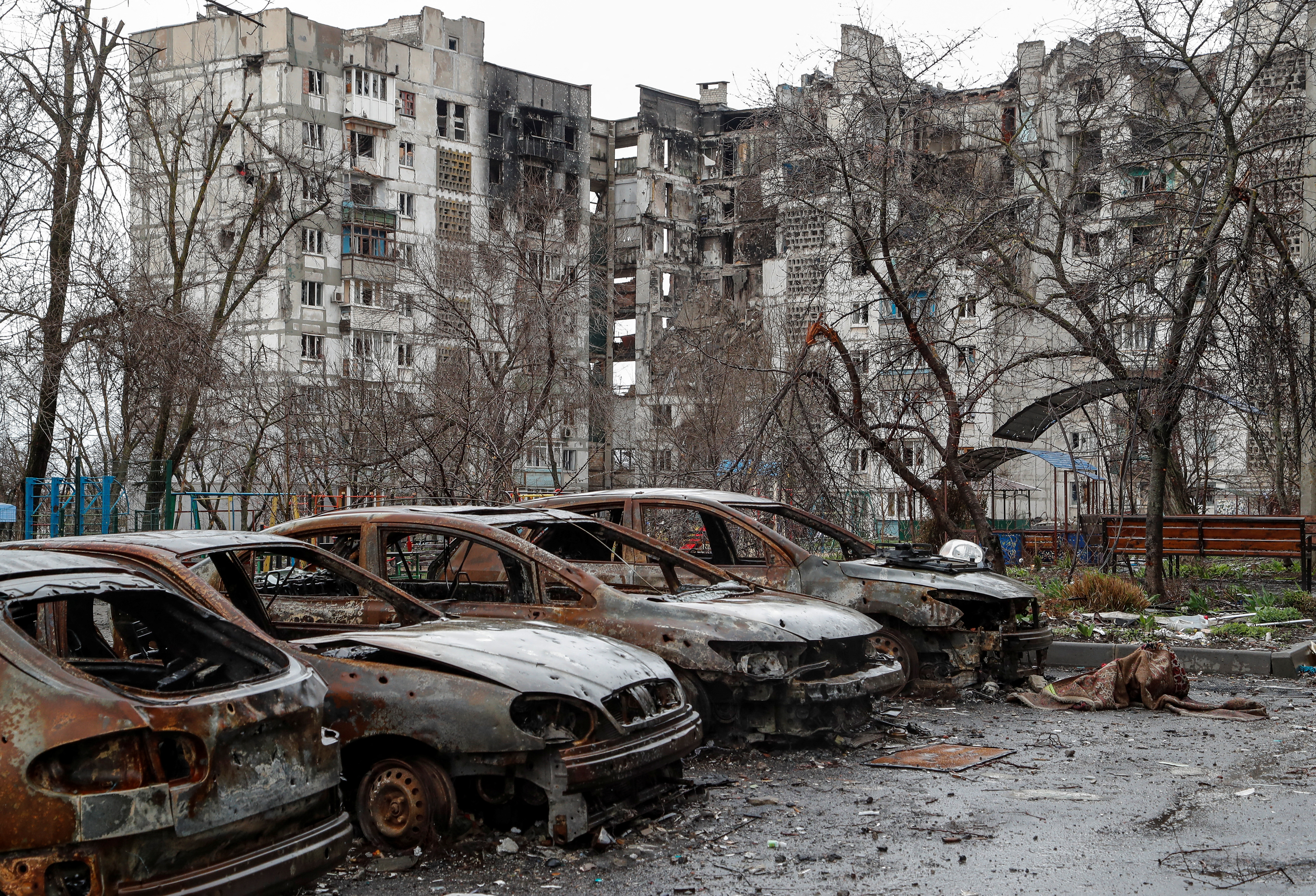 Burnt cars are seen in front of a residential building in Mariupol