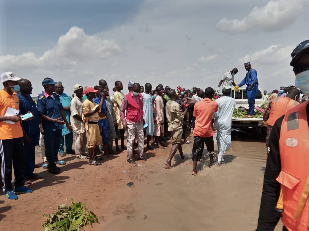 People are seen gathered around a truck as a boy, one of the victim of a boat accident, is being carried to a truck in Kebbi
