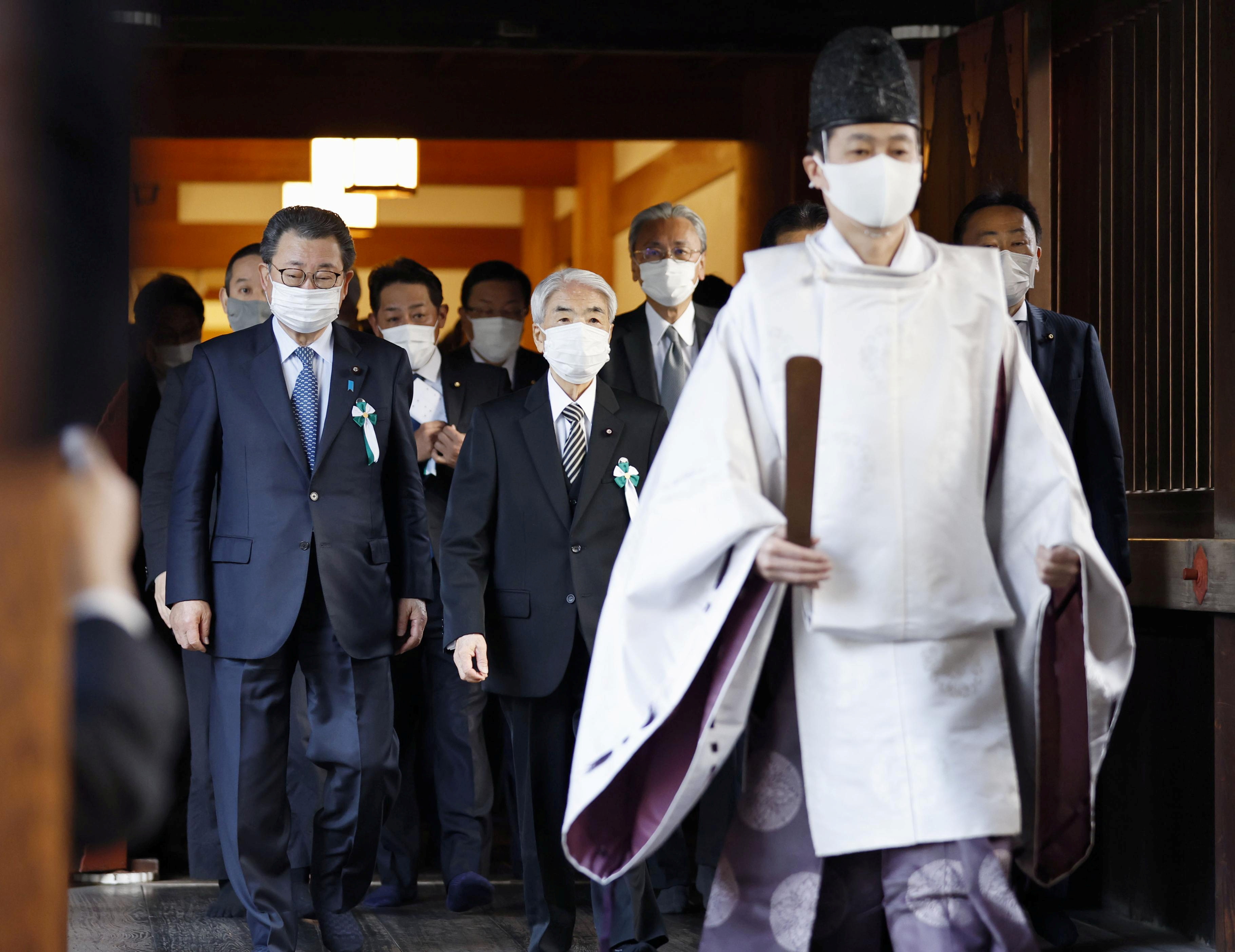A Shinto priest accompanies a group of Japanese lawmakers as they visit the Yasukuni shrine to pay respects to the country's war dead in Tokyo