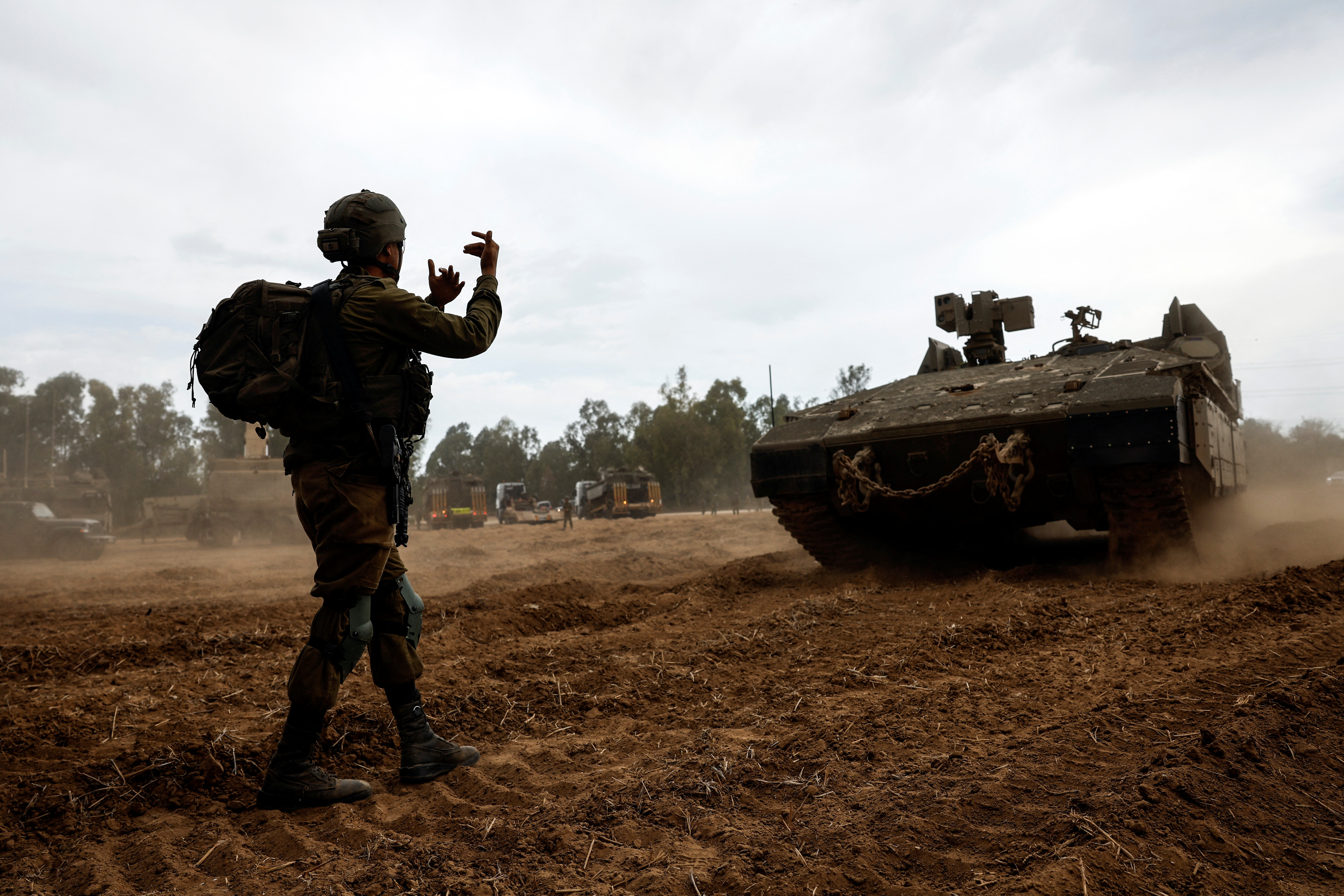 An Israeli soldier directs an Armoured Personnel Carrier (APC) at the Israeli side of the Gaza border, as violence around the nearby Gaza Strip mounts following a mass-rampage by armed Palestinian infiltrators
