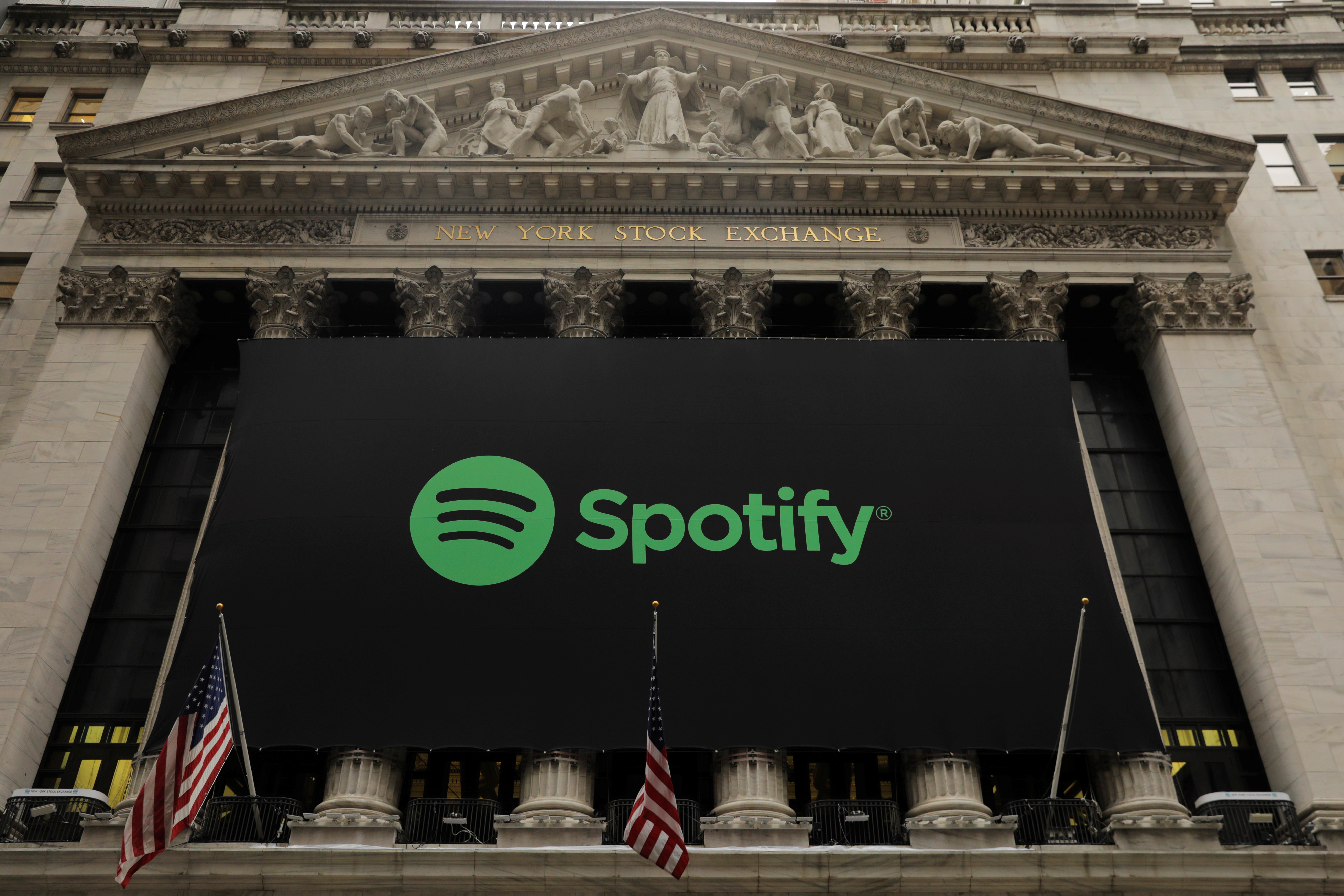 The Spotify logo hangs on the facade of the New York Stock Exchange as the company lists its stock with a direct listing in New York