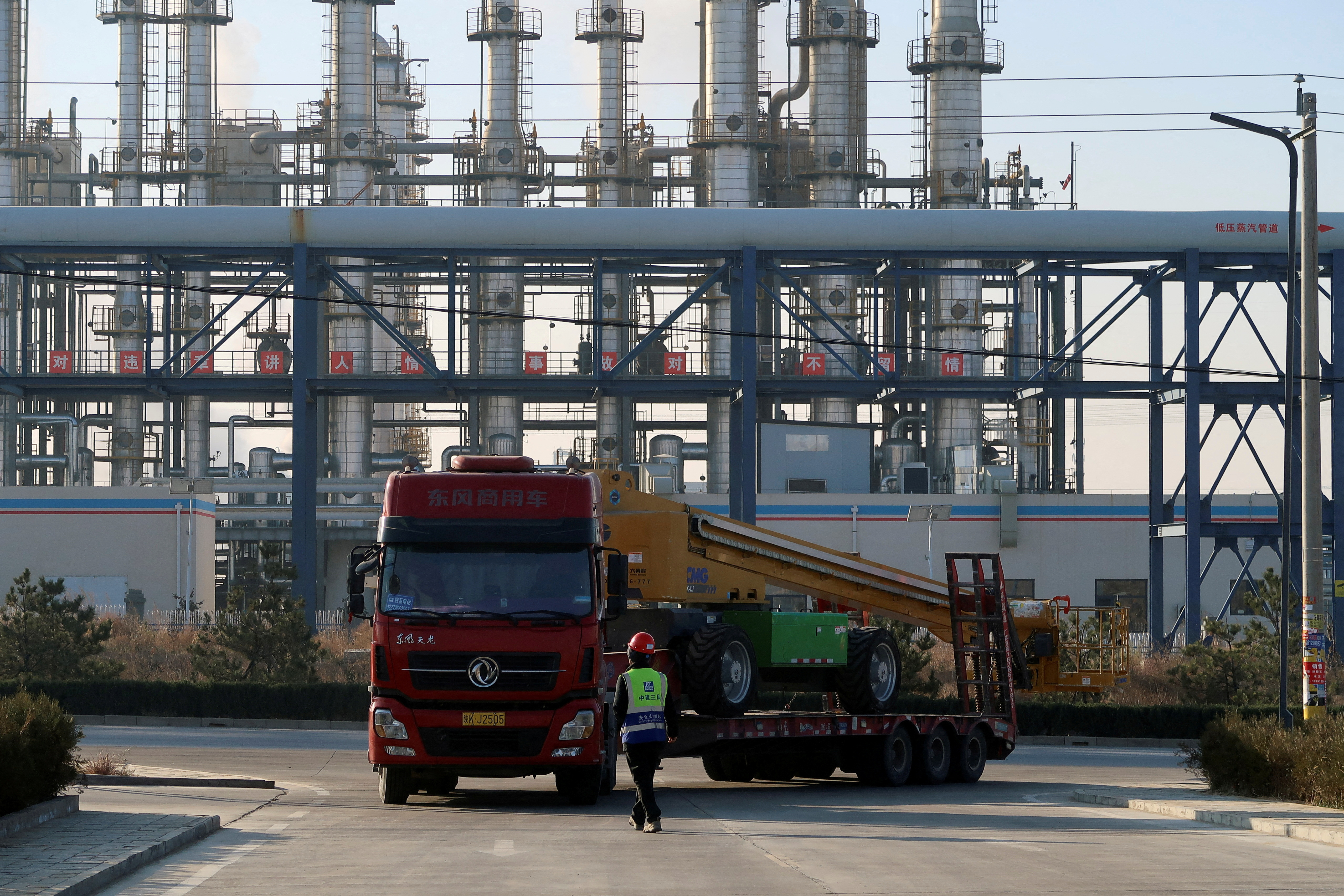 Worker directs a truck outside the gate of Yushen Yuheng power plant, a coal-fired power plant under construction, in Yulin