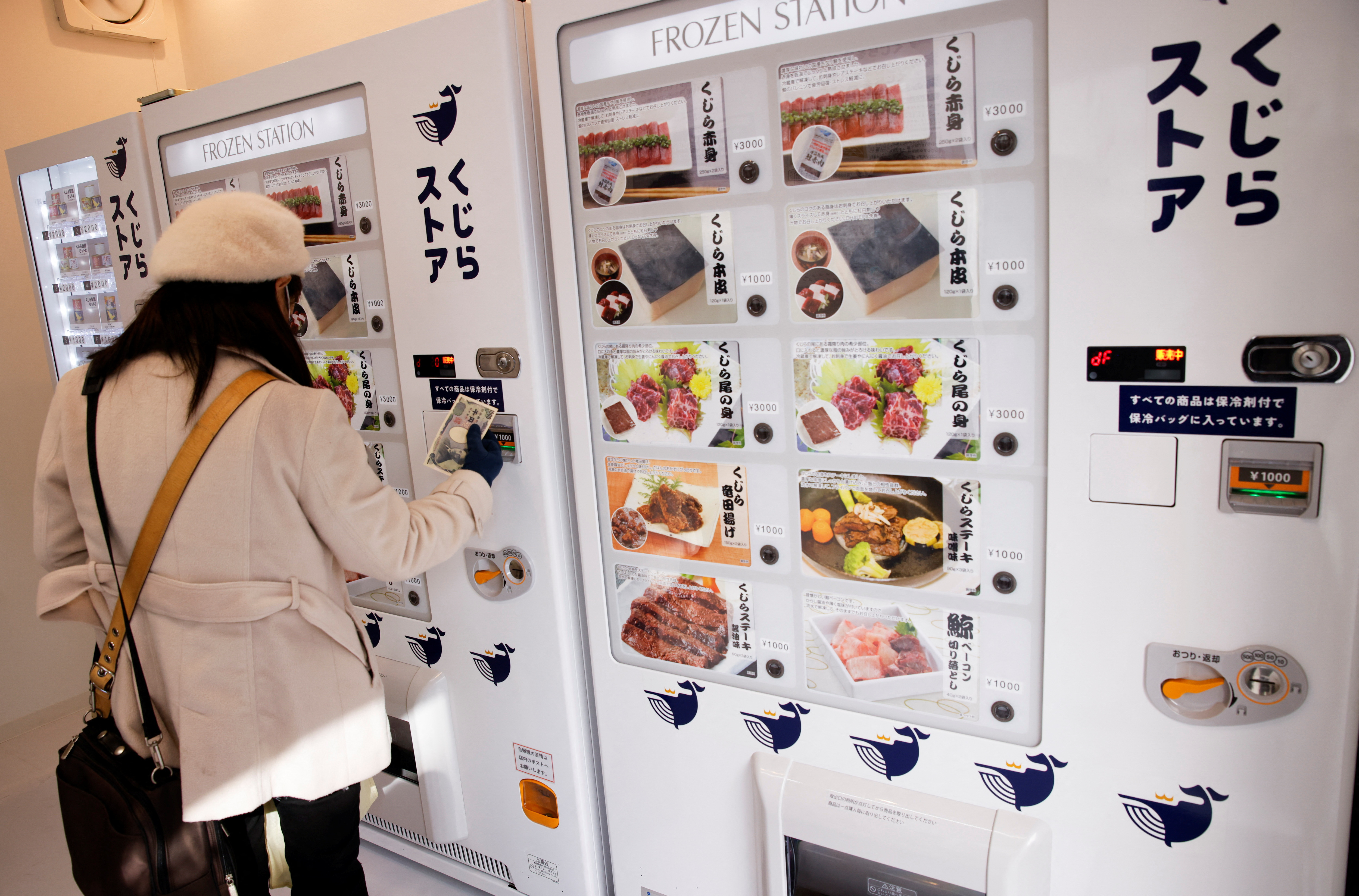 A customer buys whale meat on the opening day of the shop by a Japanese whale-hunting company with vending machines in Yokohama