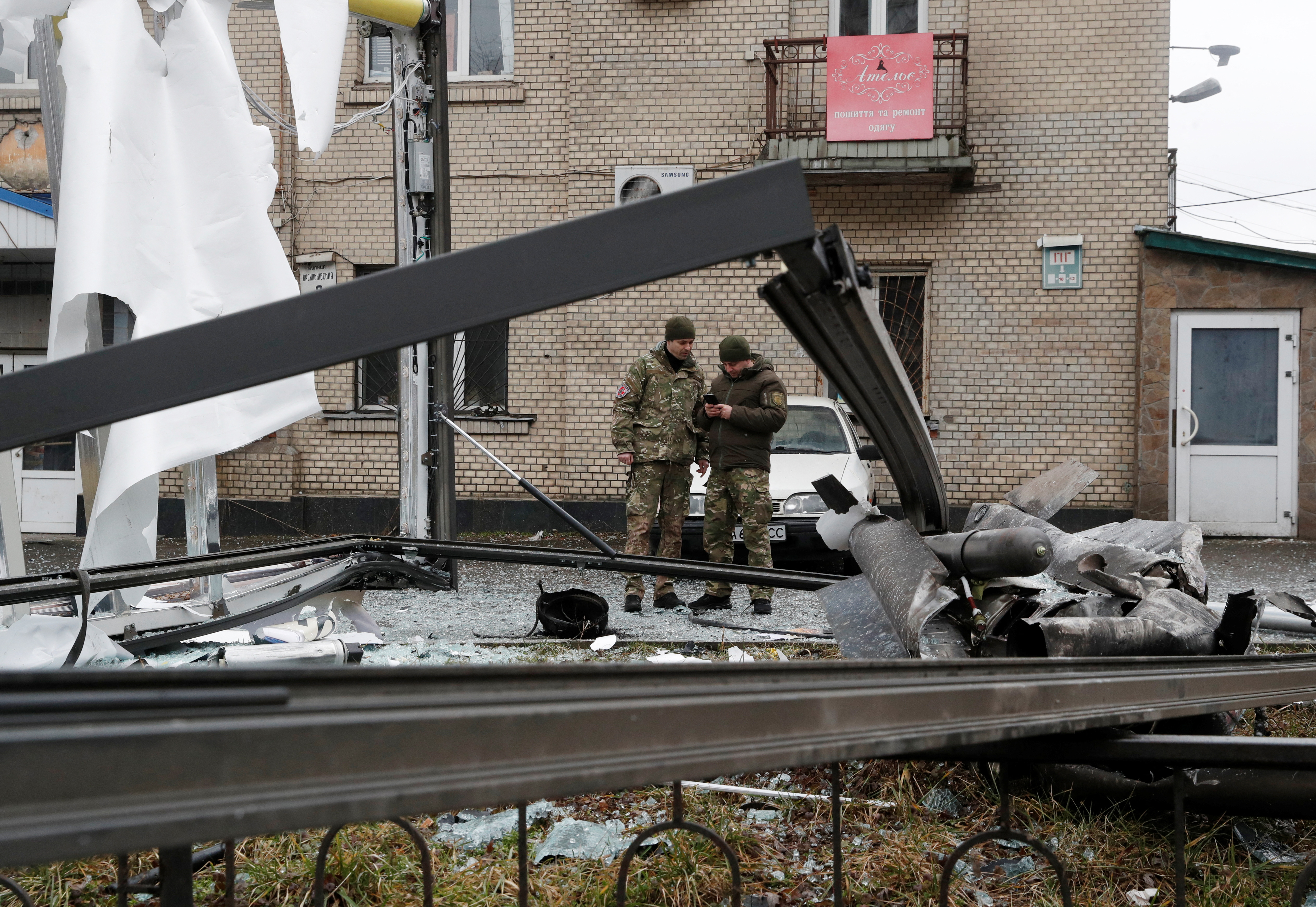 Police officers inspect the remains of a missile that fell in the street in Kyiv