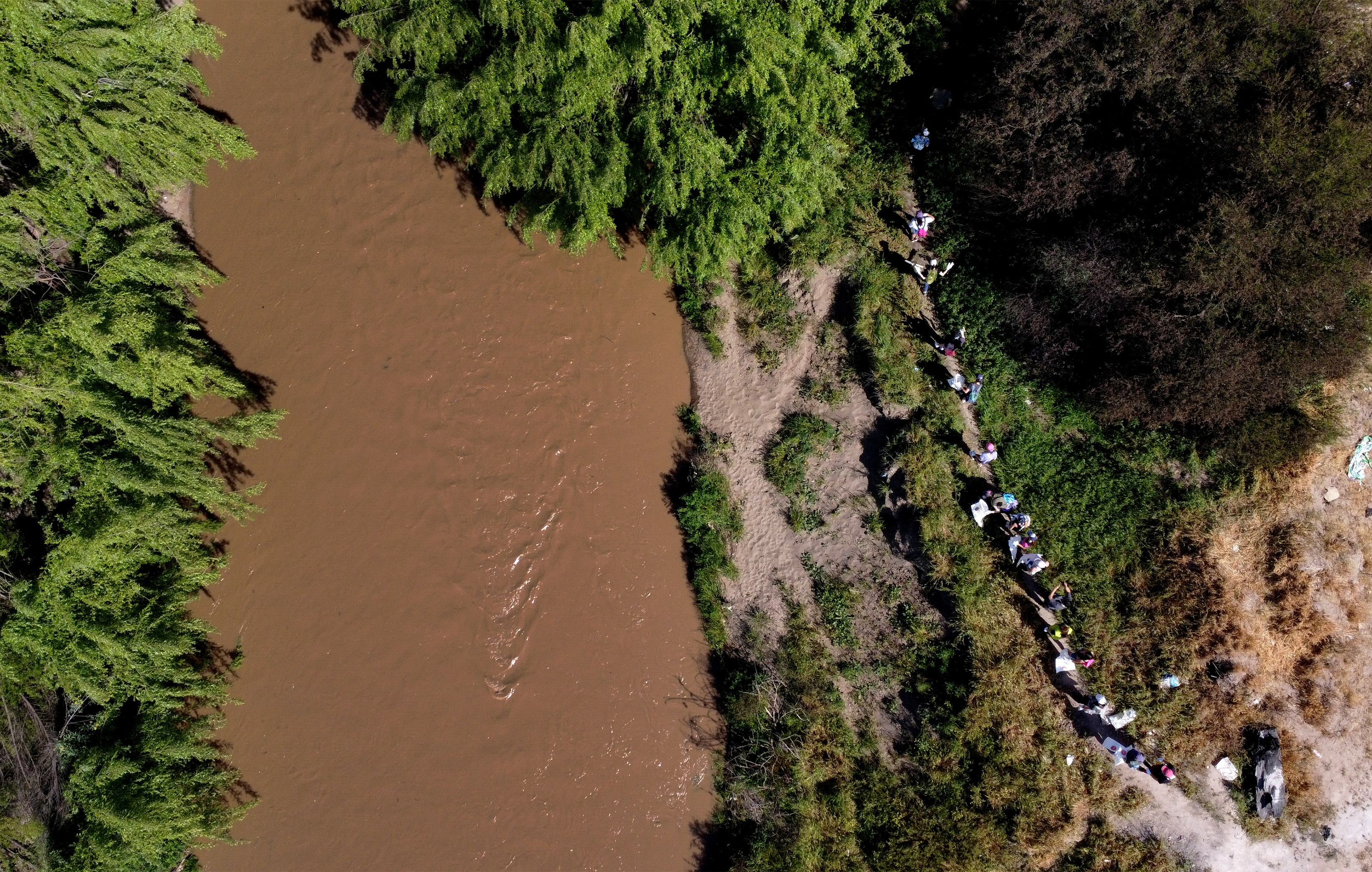 An aerial view shows a group volunteers walking on a path to clean the Mapocho river bank in Santiago