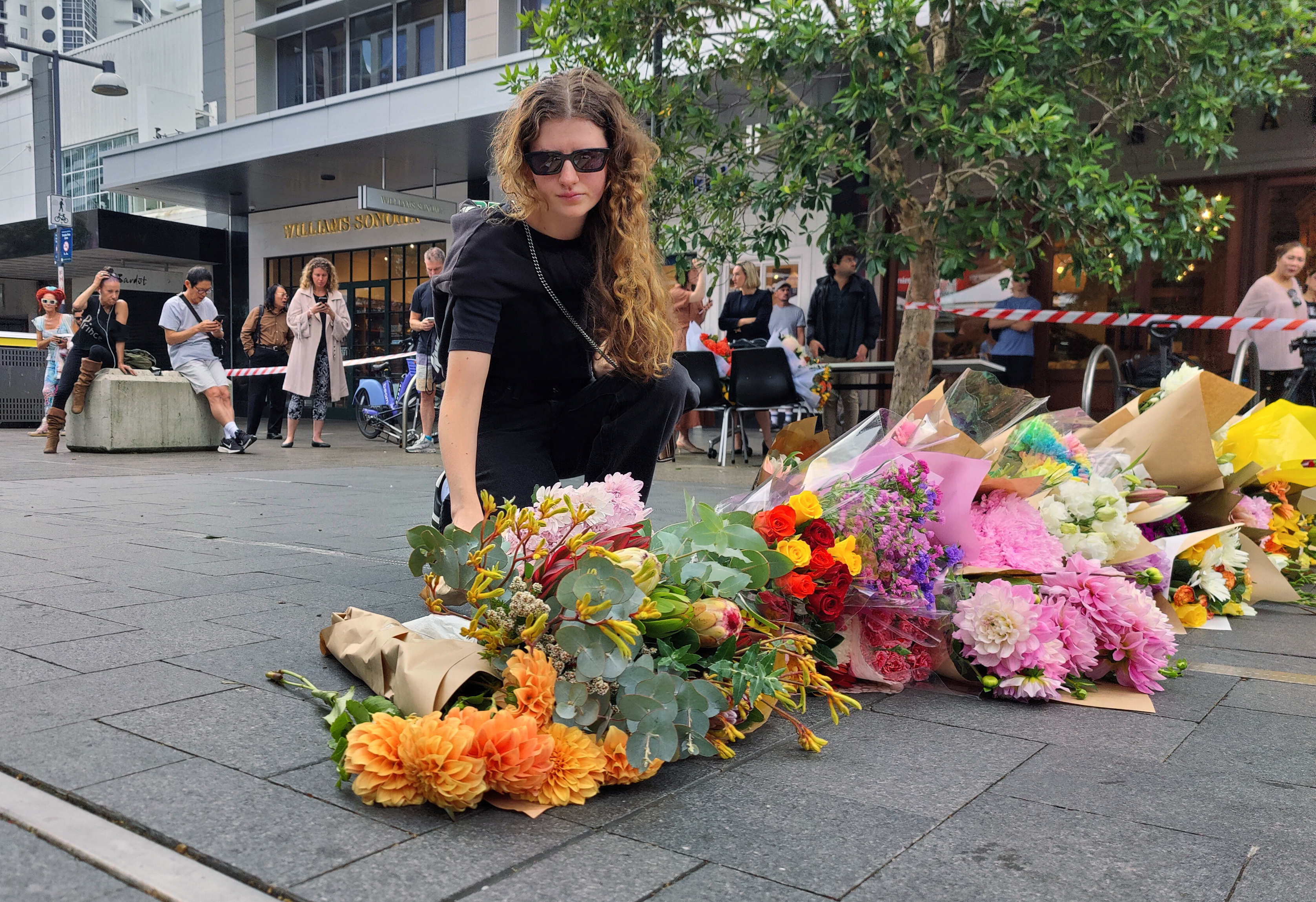 People offer flowers for the victims of Saturday's stabbings at Bondi Junction in Sydney
