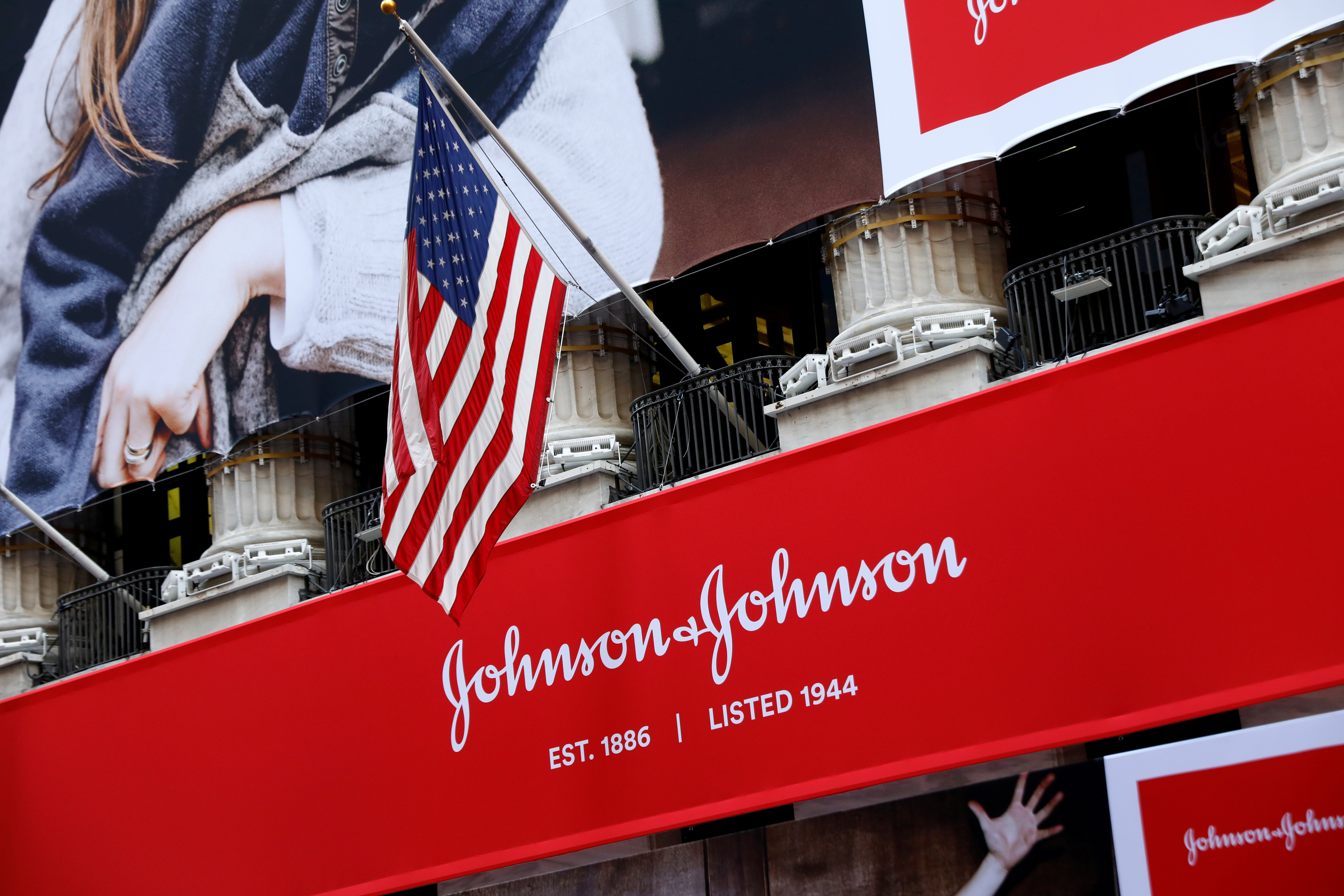 The U.S. flag is seen over the company logo for Johnson & Johnson to celebrate the 75th anniversary of the company's listing at the NYSE in New York