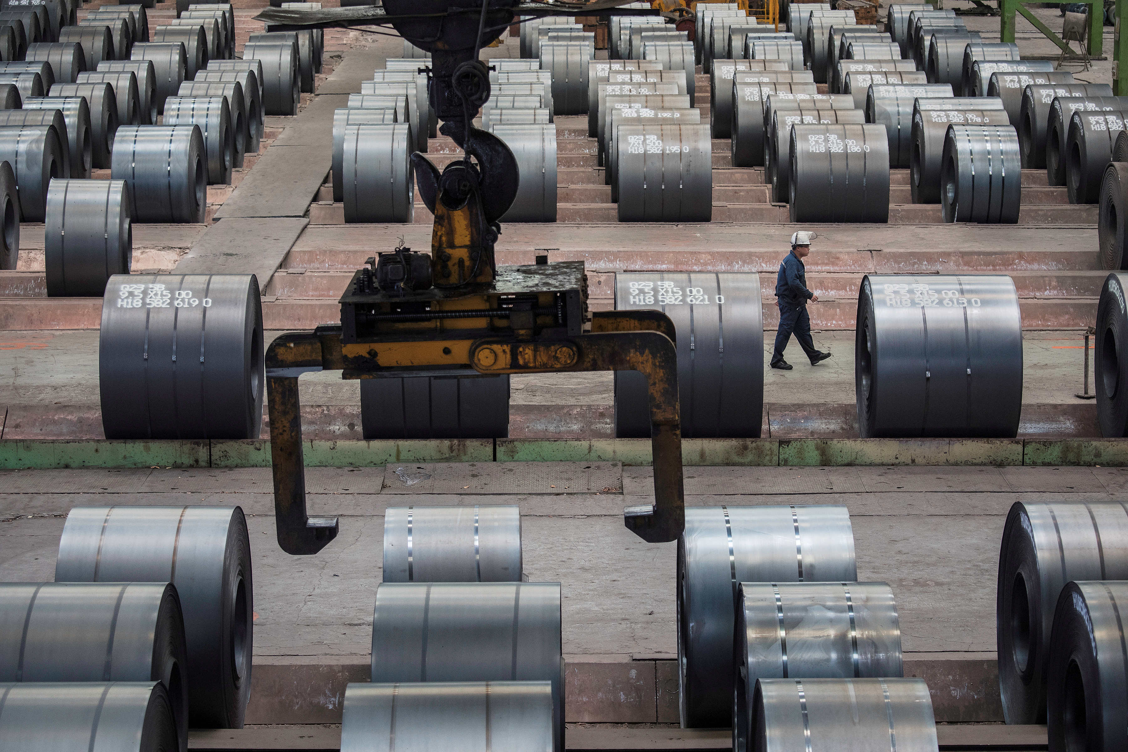 Worker walks past steel rolls at the Chongqing Iron and Steel plant in Changshou