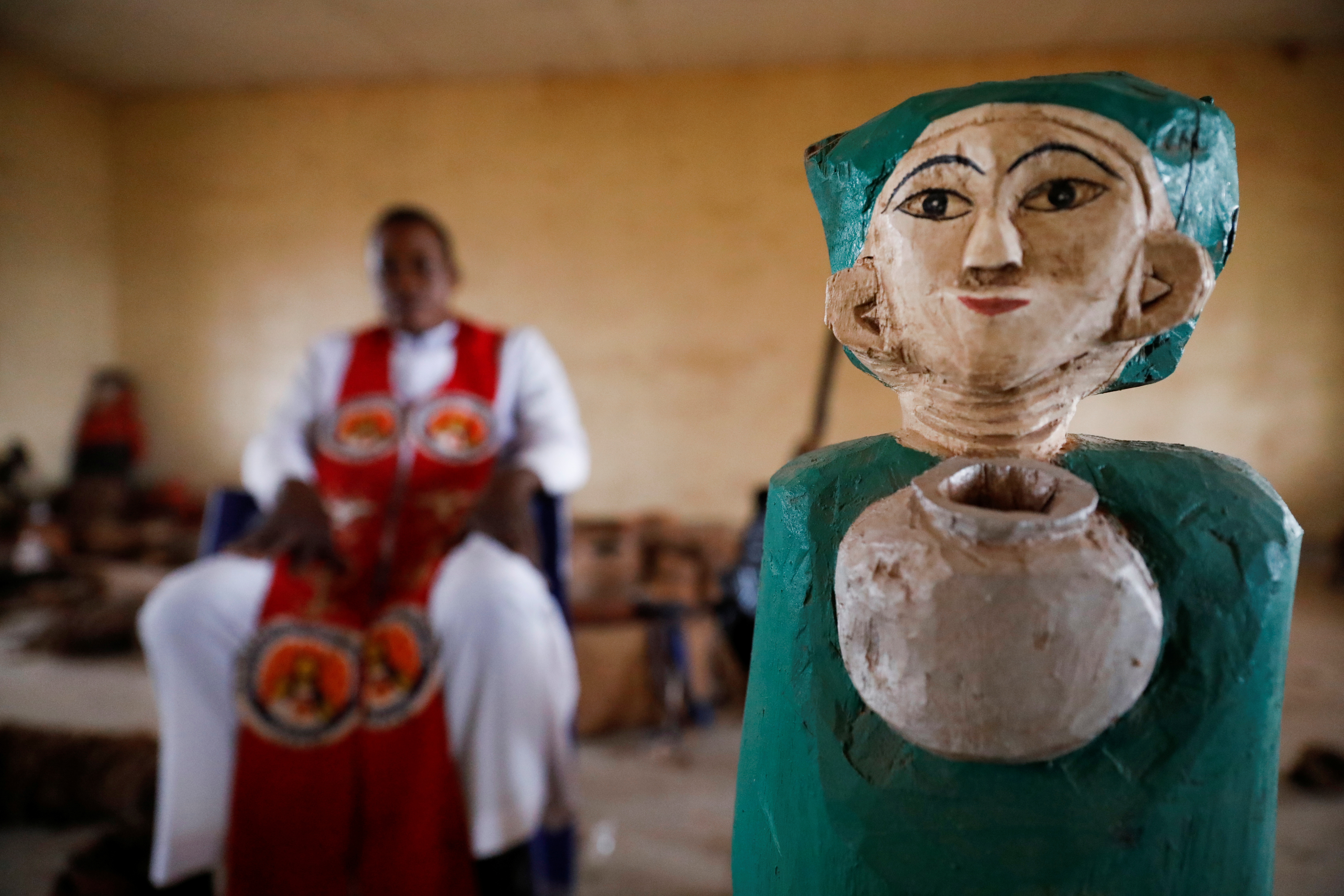 Reverend Father Paul Obayi sits beside a wooden artefact that was recovered from a shrine and stored in his museum in Nsukka, Enugu Nigeria September 29, 2021. Picture taken September 29, 2021. REUTERS/Temilade Adelaja