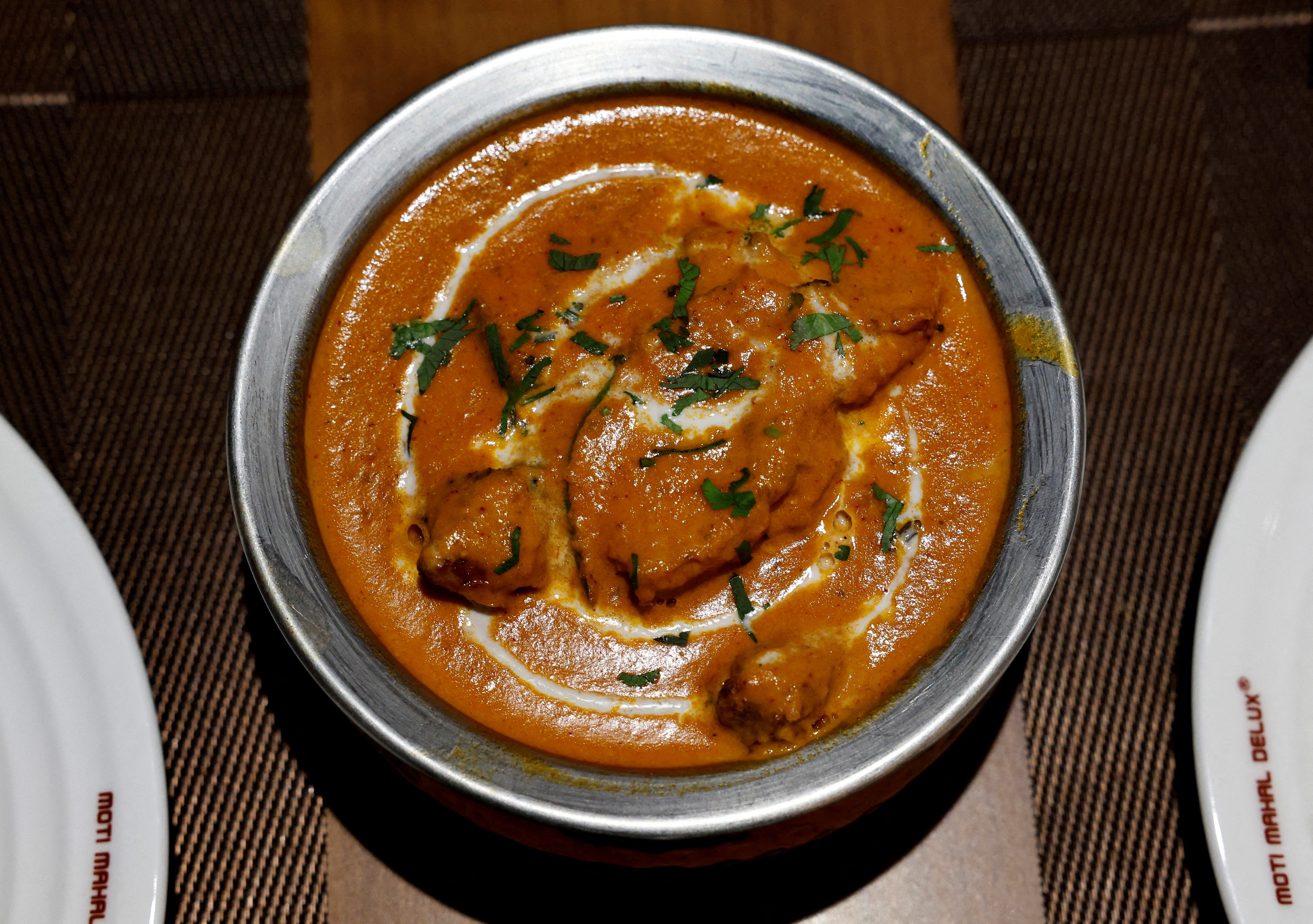 A freshly prepared butter chicken dish is placed on a table inside the Moti Mahal Delux restaurant in New Delhi
