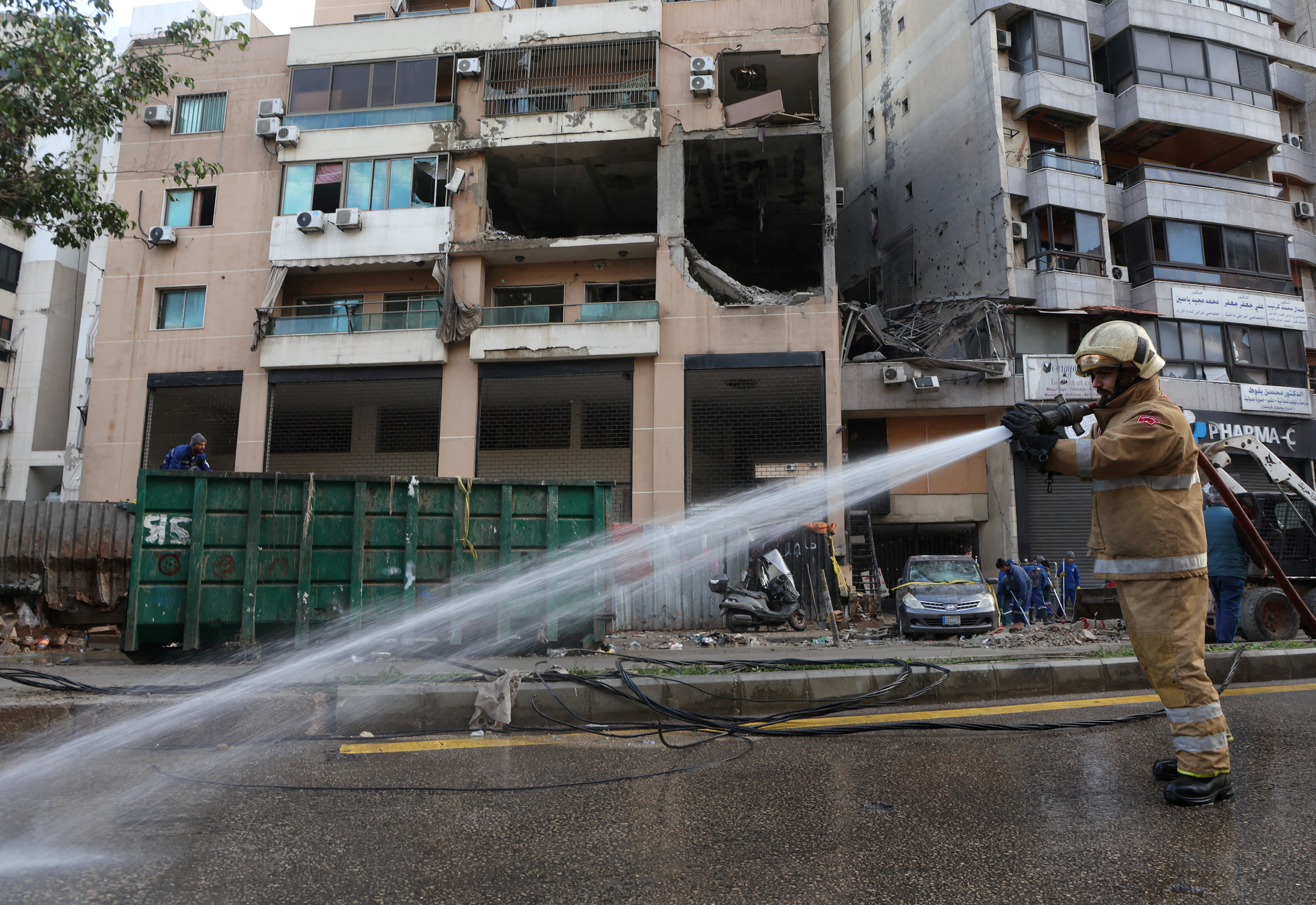 Hezbollah affiliated civil defence member sprays water at a damaged site in the aftermath of what security sources said was an Israeli drone strike in Beirut's southern suburbs of Dahiyeh