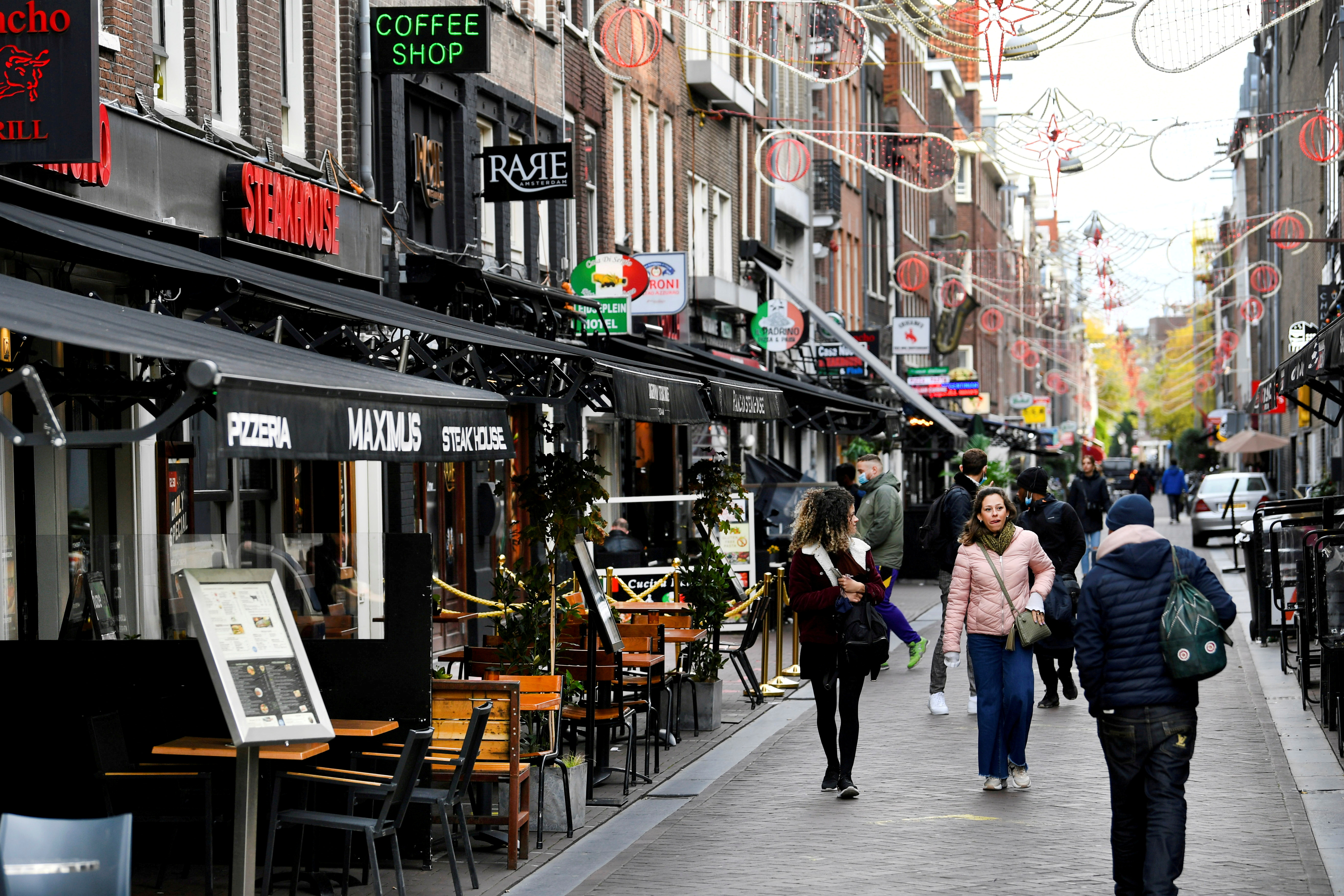 People walk past restaurants and bars in Amsterdam.
