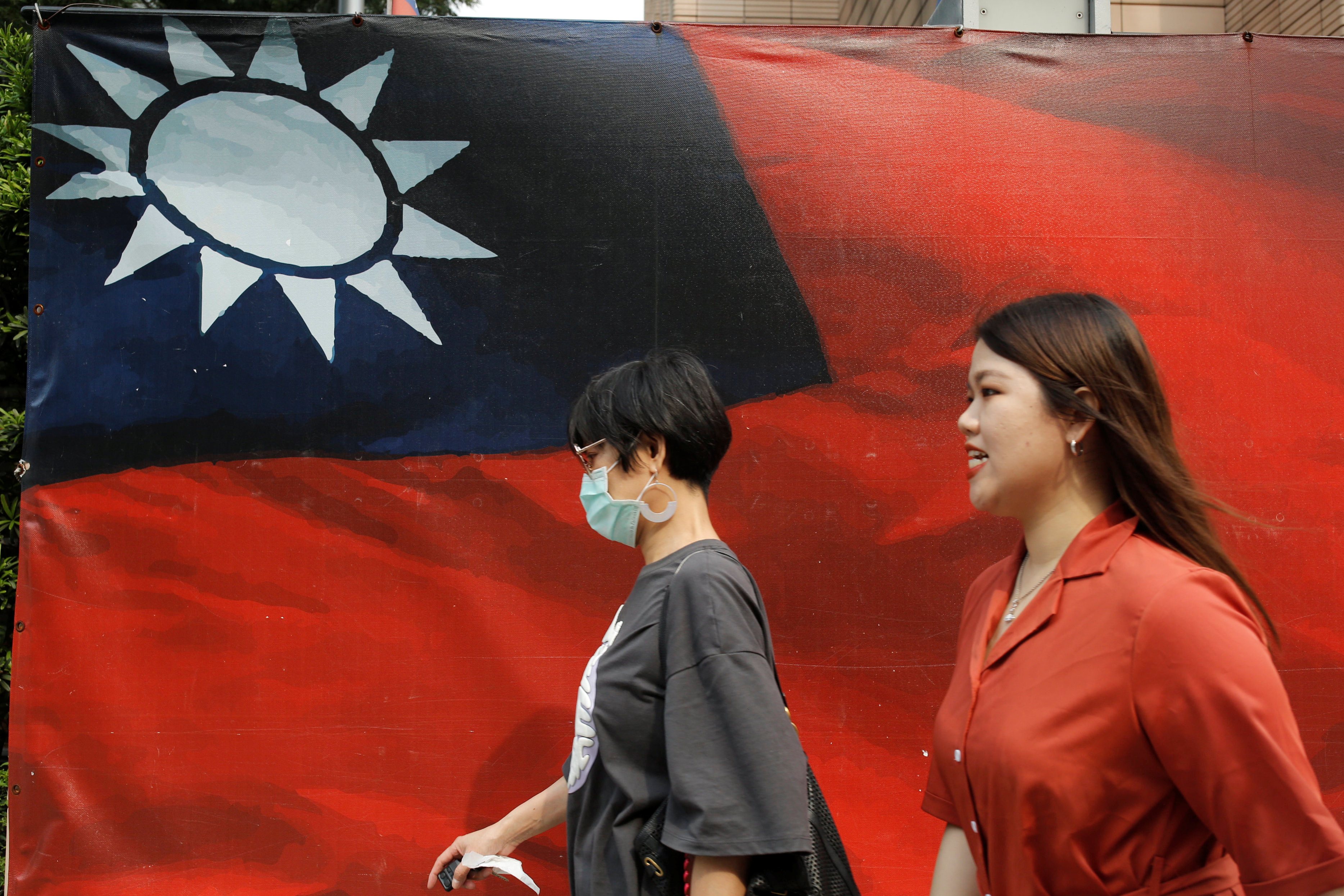 People walk past a Taiwan flag in Taipei