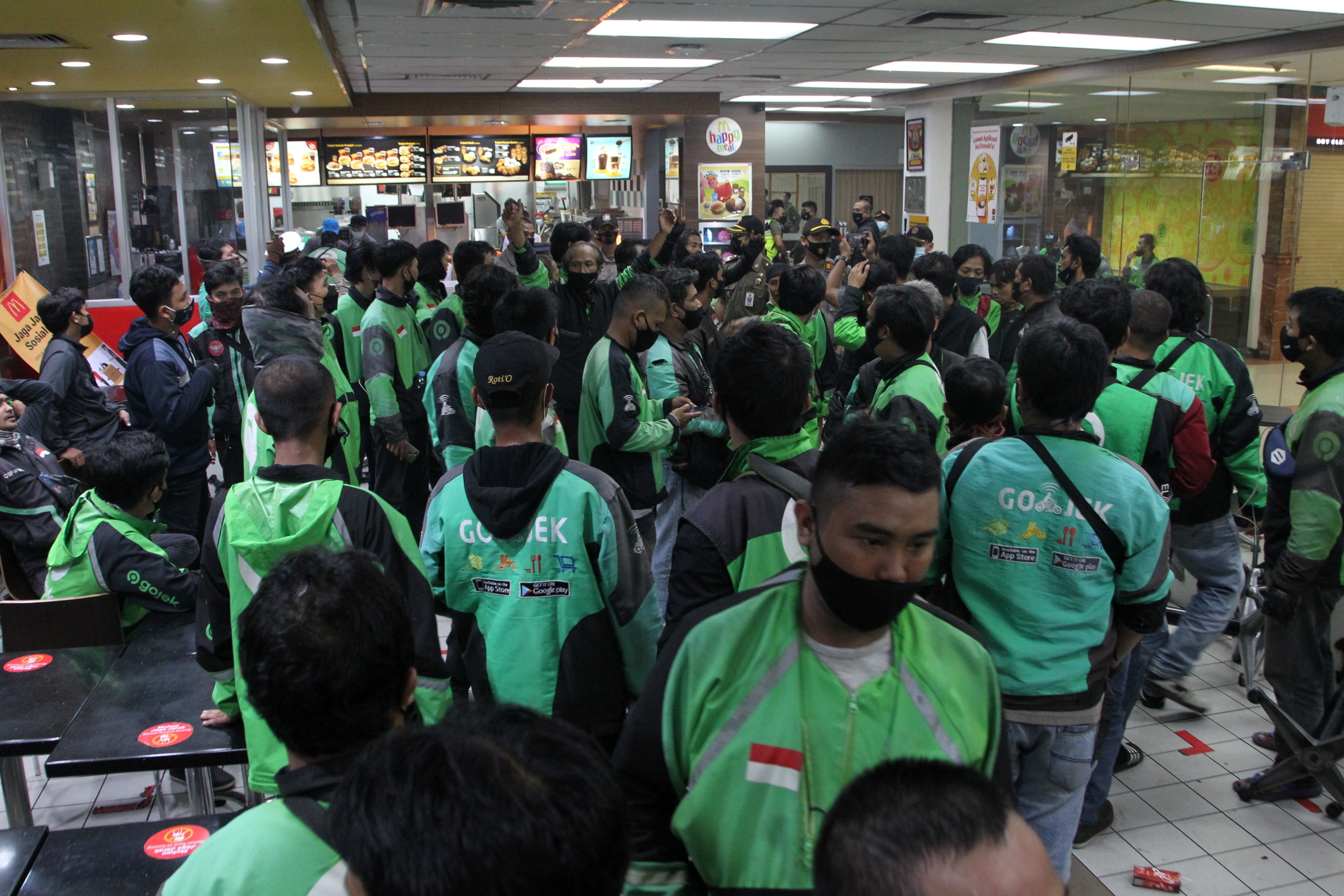 Food delivery drivers crowd in a McDonald's restaurant as they wait for BTS meal orders, in Bogor