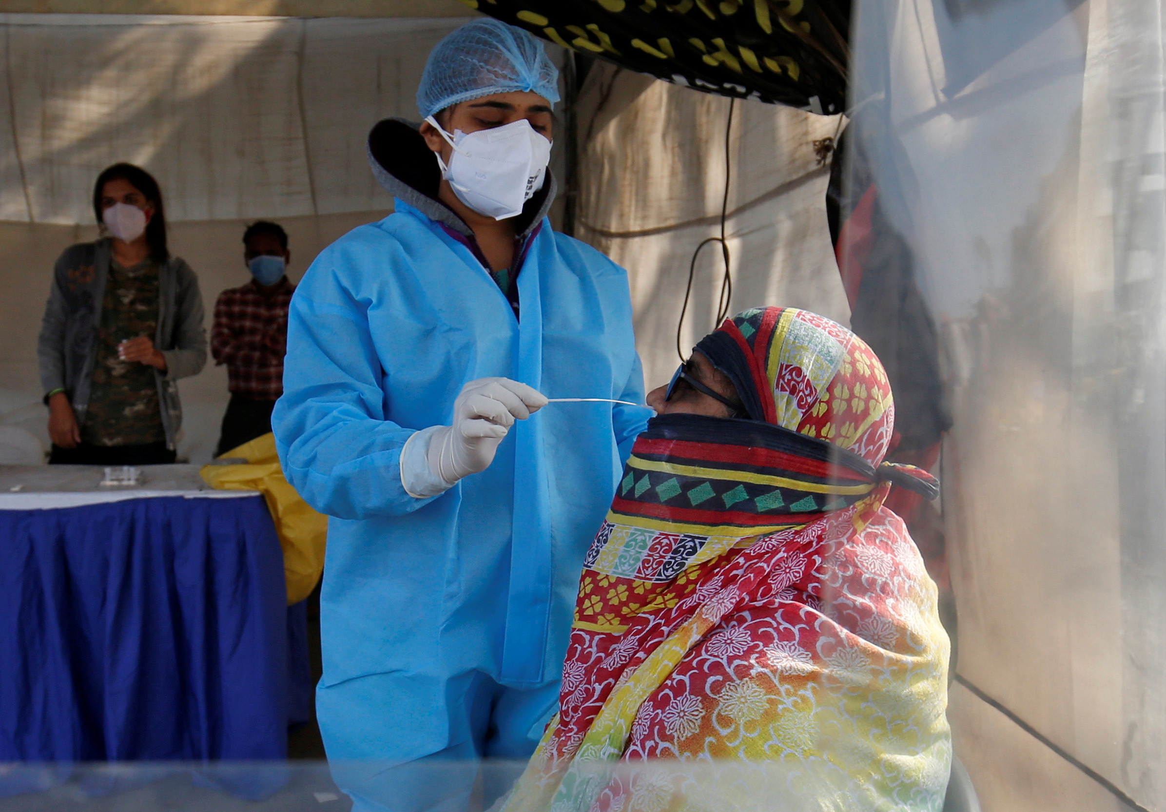 A healthcare worker collects a swab sample from a woman during a rapid antigen testing campaign for the coronavirus disease (COVID-19), in Ahmedabad