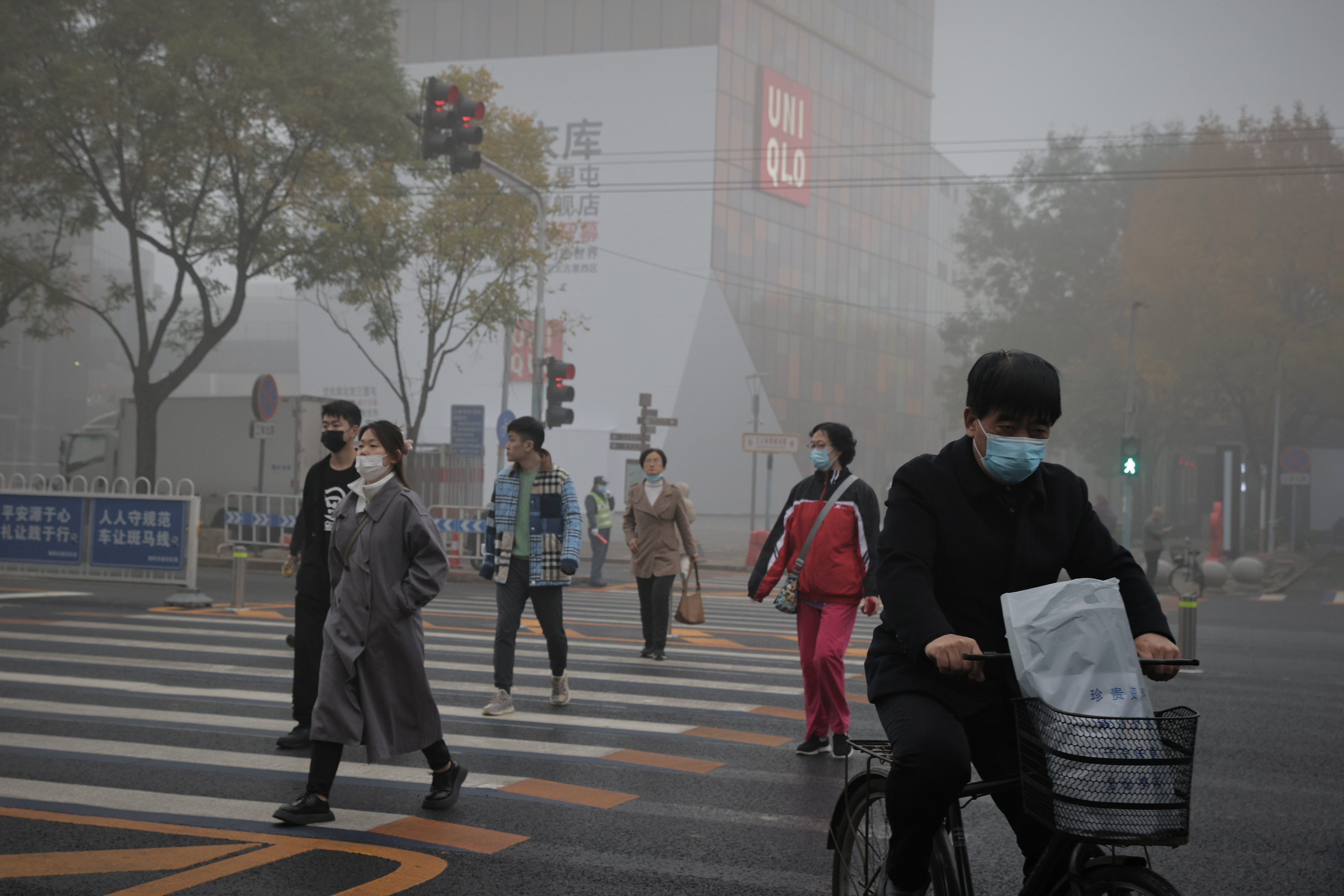 People cross a street in the Sanlitun shopping district on a polluted day in Beijing