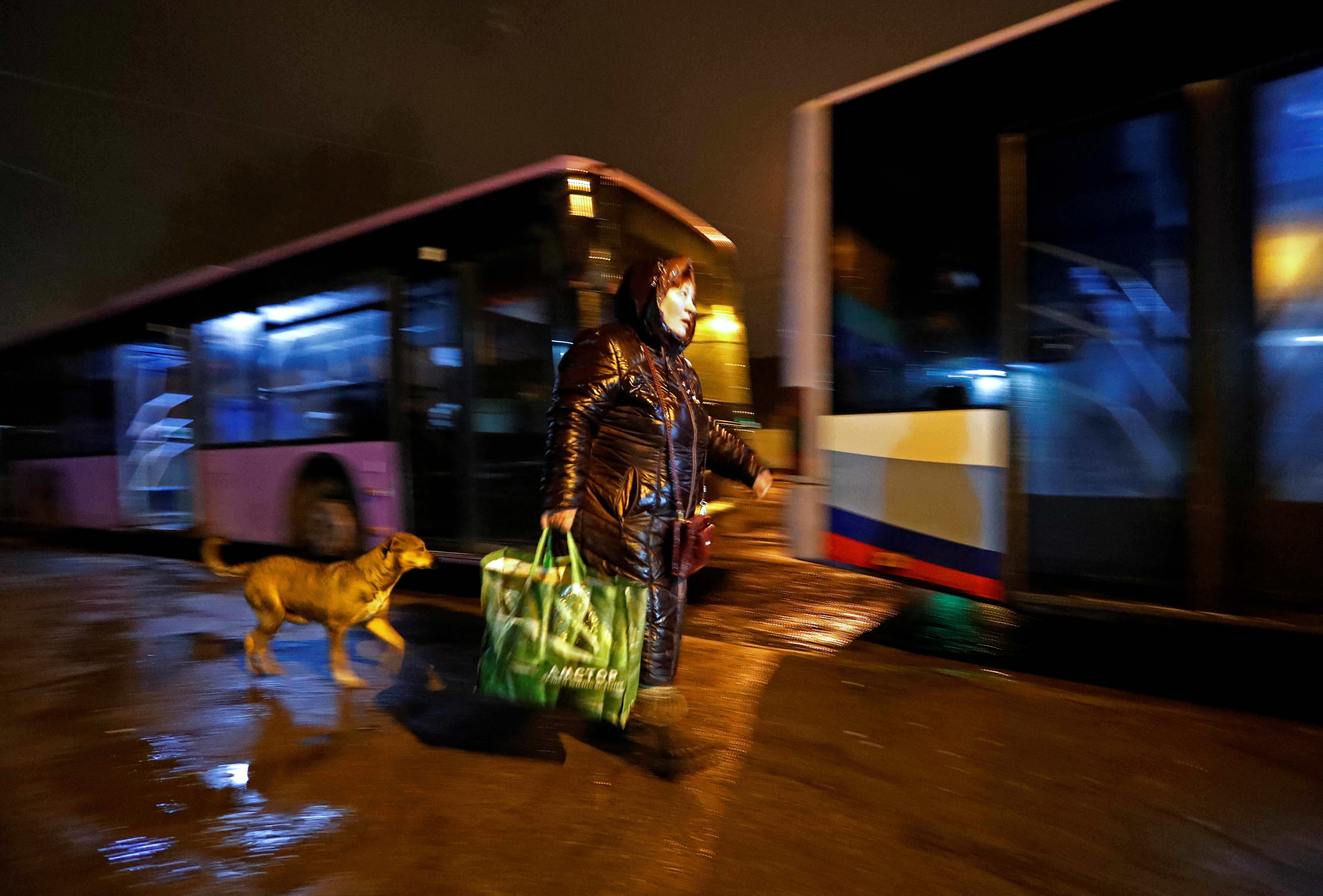 A woman walks to board a bus arranged to evacuate local residents, in Donetsk