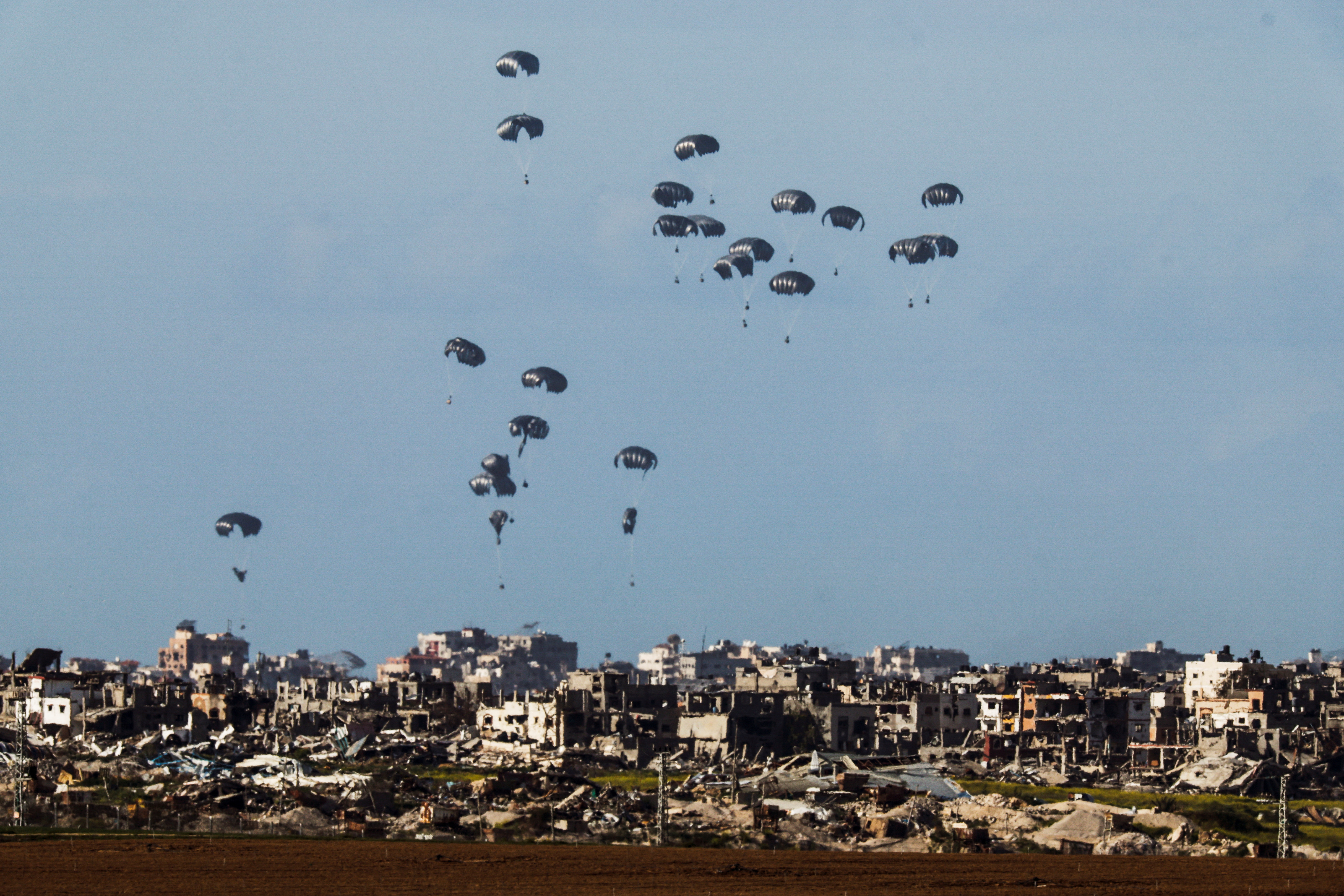 Packages dropped from a military aircraft fall towards northern Gaza, as seen from Israel