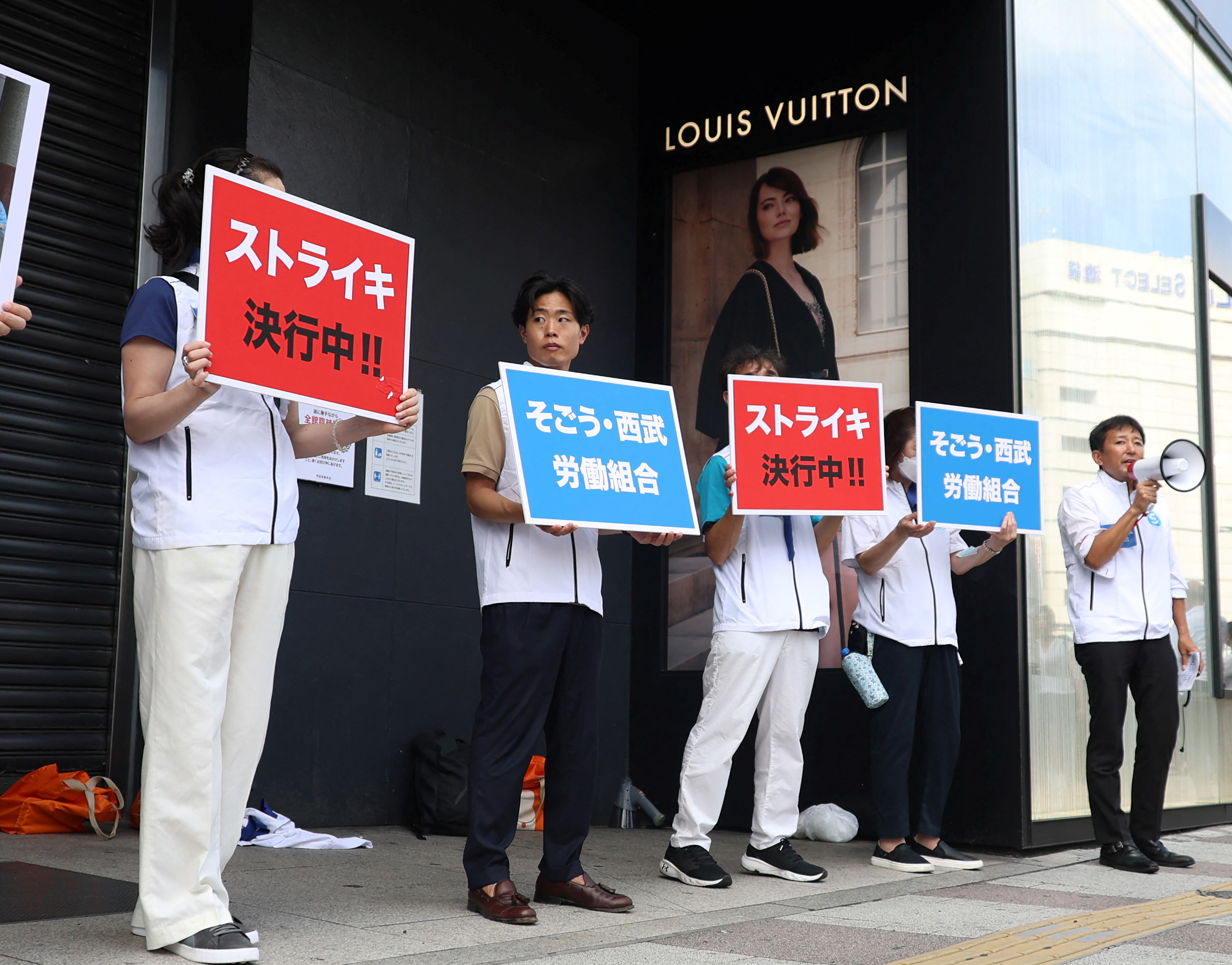 Union workers of Sogo &?Seibu hold banners which read 'on strike' in front of the company's flagship?Seibu?Ikebukuro store in Tokyo