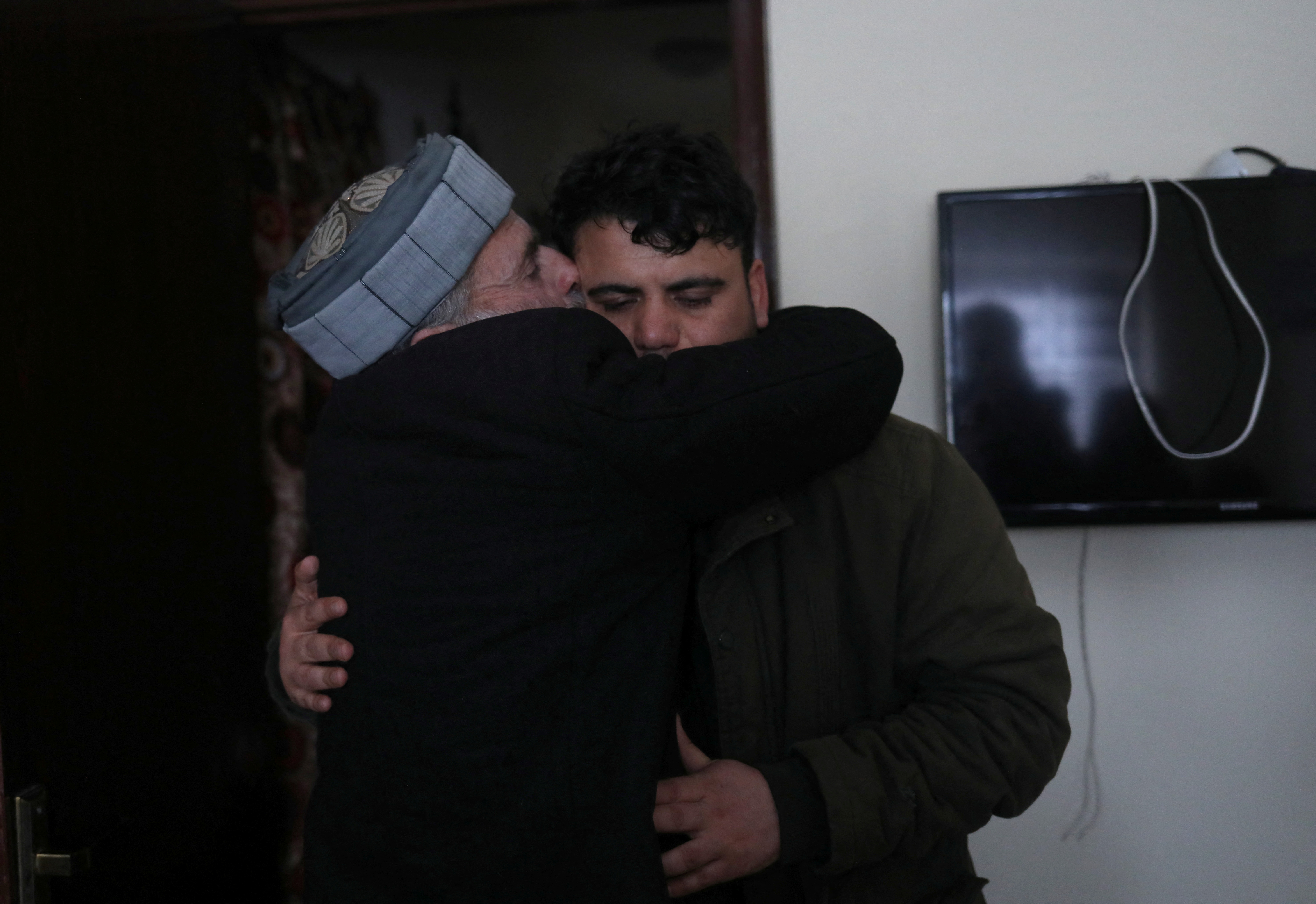 Hamid Safi, a 29-year-old taxi driver who had found baby Sohail Ahmadi in the airport, is kissed by Sohail's grandfather Mohammad Qasem Razawi at his home in Kabul