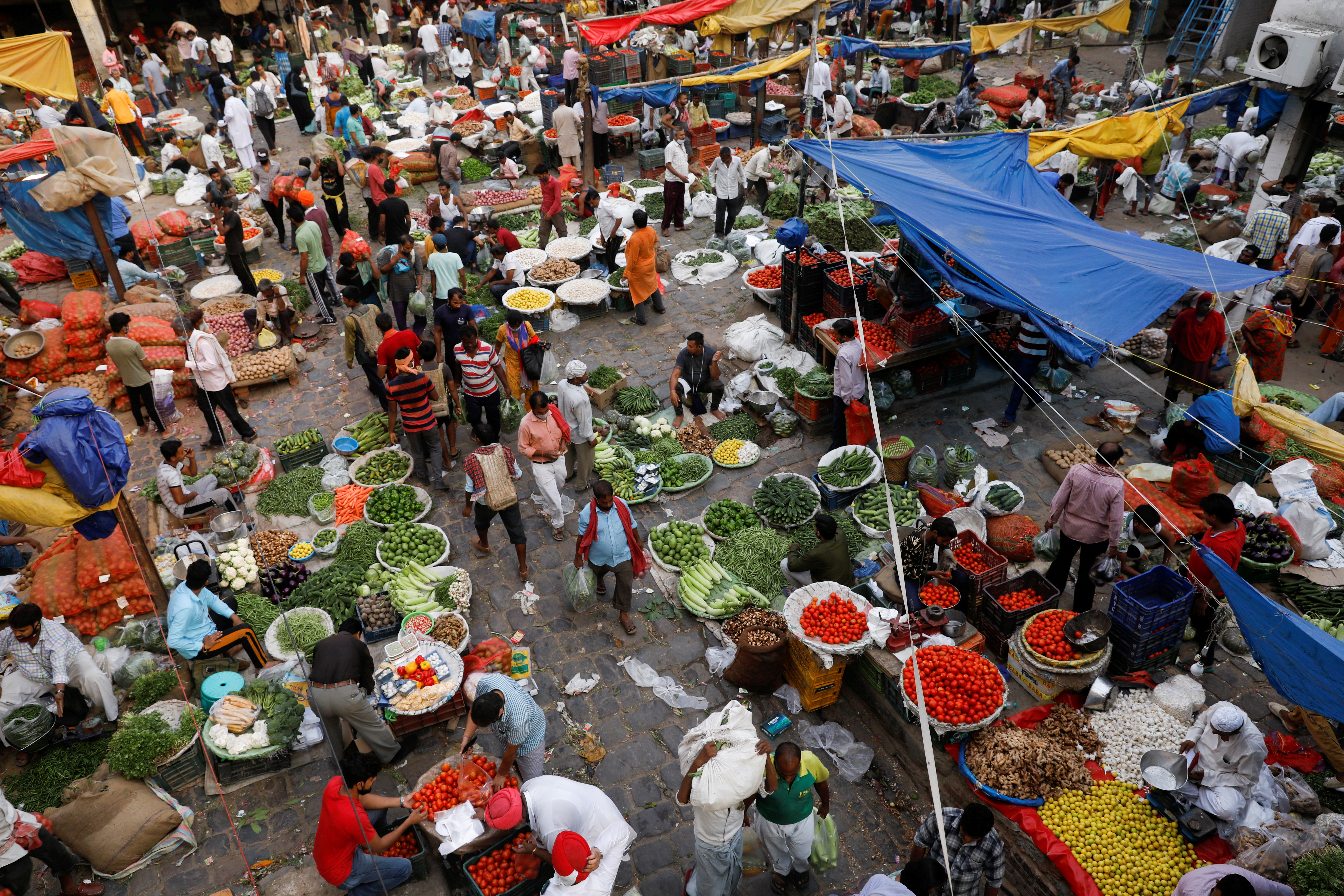 People shop at a crowded wholesale vegetable market after authorities eased coronavirus restrictions, following a drop in COVID-19 cases, in the old quarters of Delhi, India, June 23, 2021. REUTERS/Adnan Abidi
